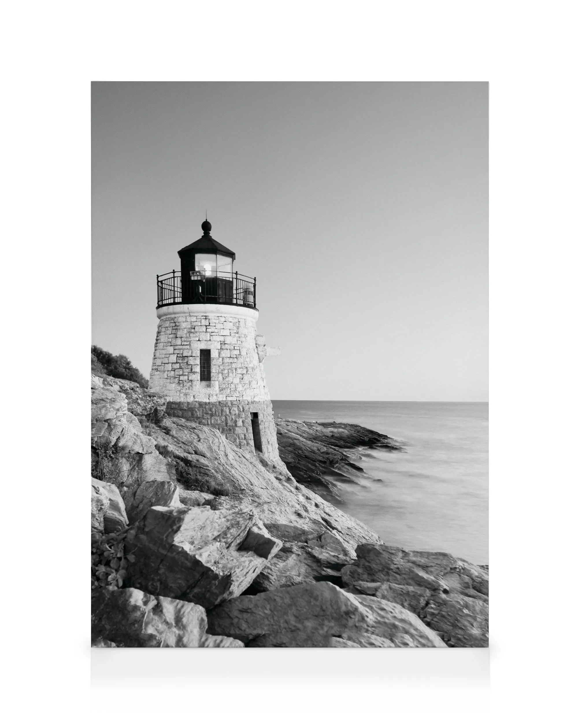 Toile noir et blanc dun petit phare en pierre sur une côte rocheuse avec une mer calme et un ciel clair.