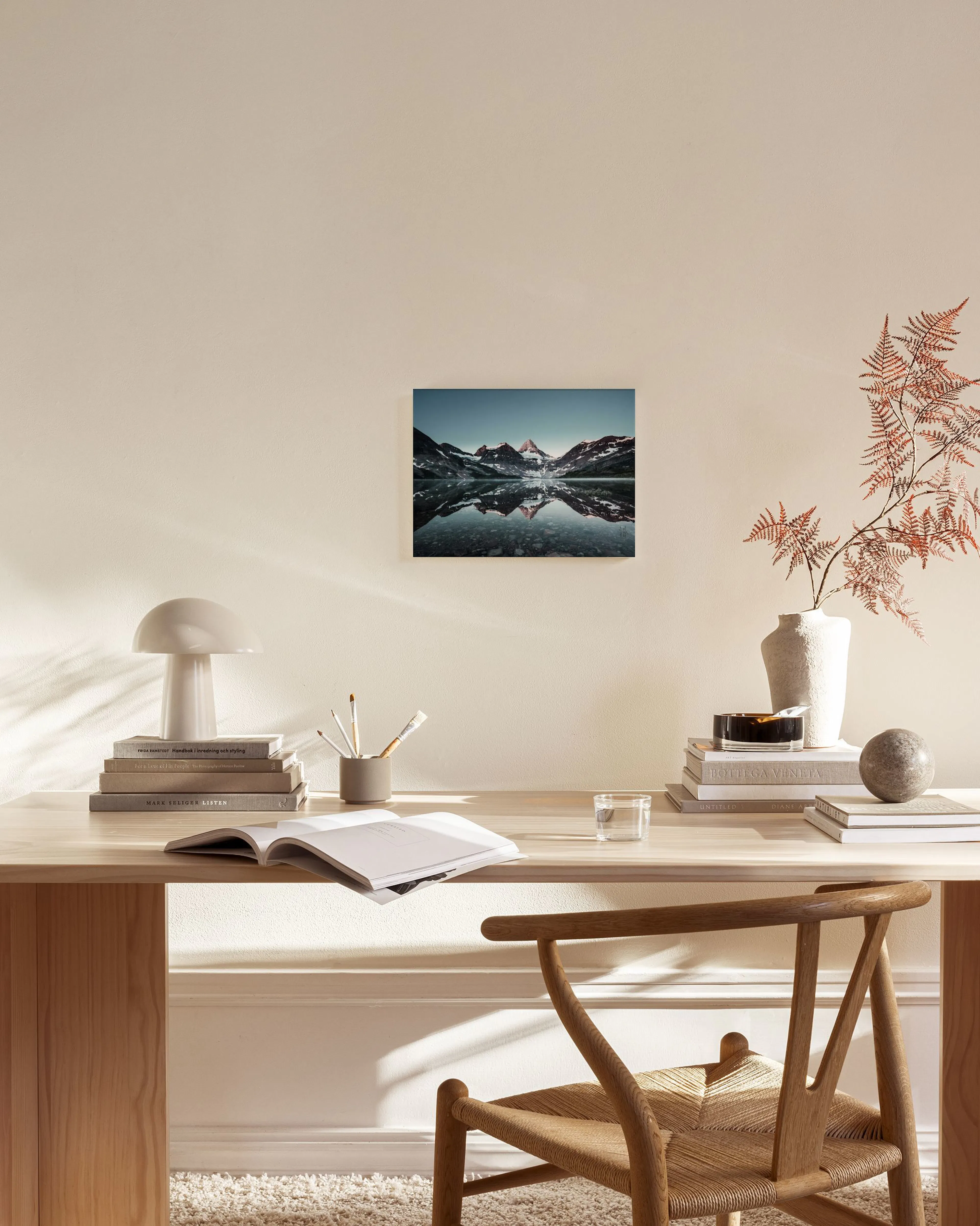 A canvas print of snow-capped mountains reflected in a still lake, hanging in a minimalist living room.