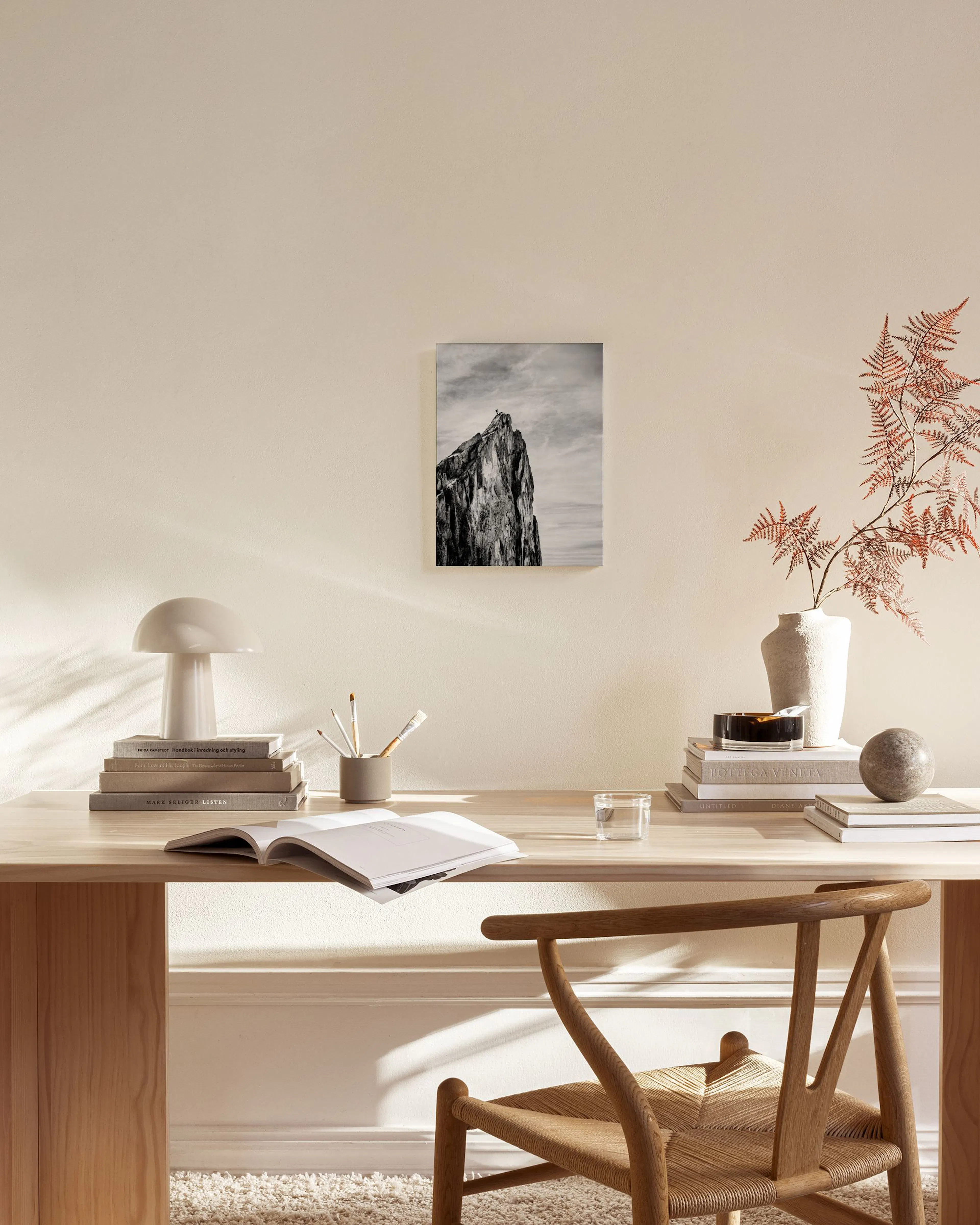 A black and white canvas print of a majestic mountain peak under a cloudy sky, displayed in a minimalist living room.