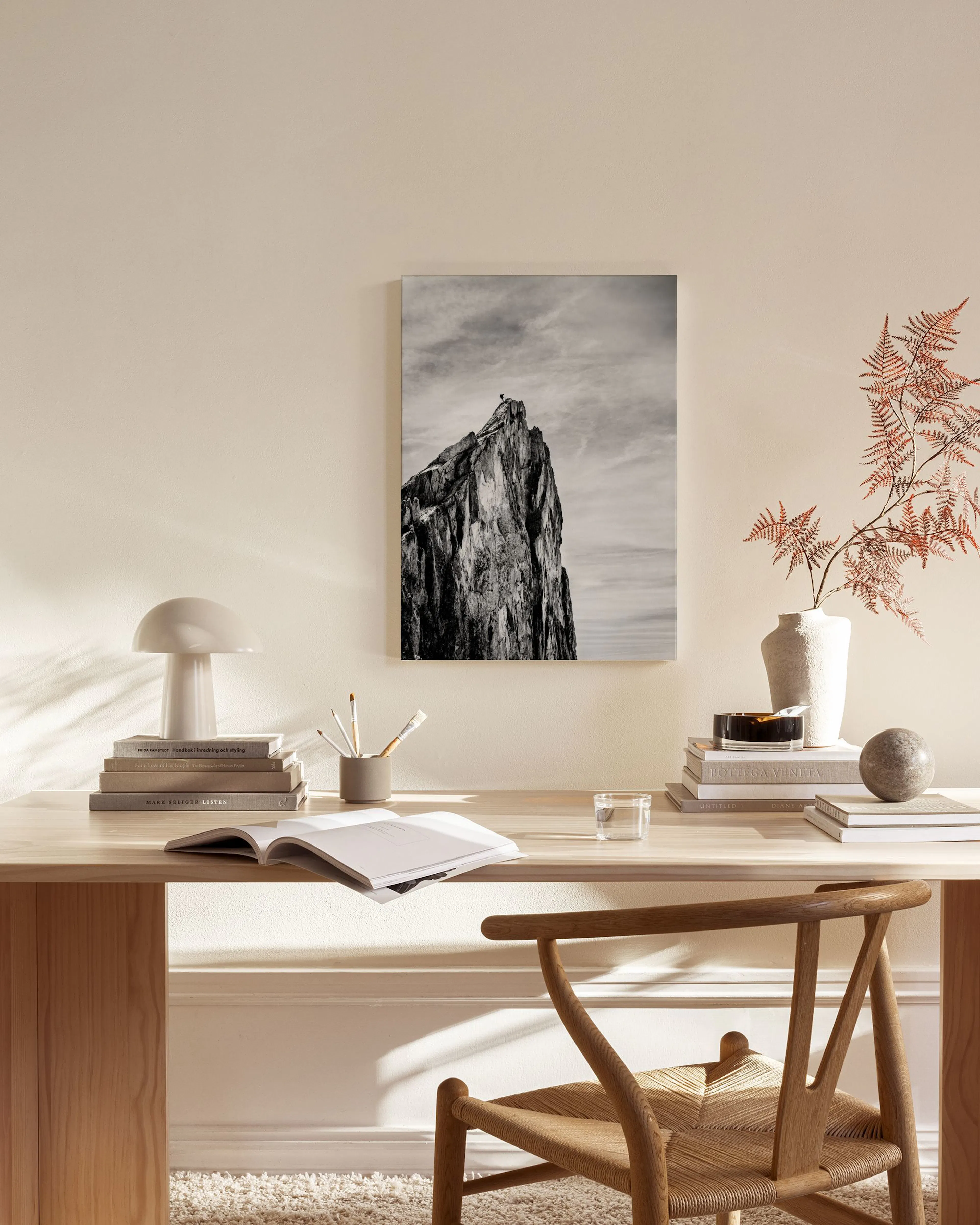 Black and white canvas print of a rugged mountain peak under a cloudy sky, hanging in a minimalist living room.
