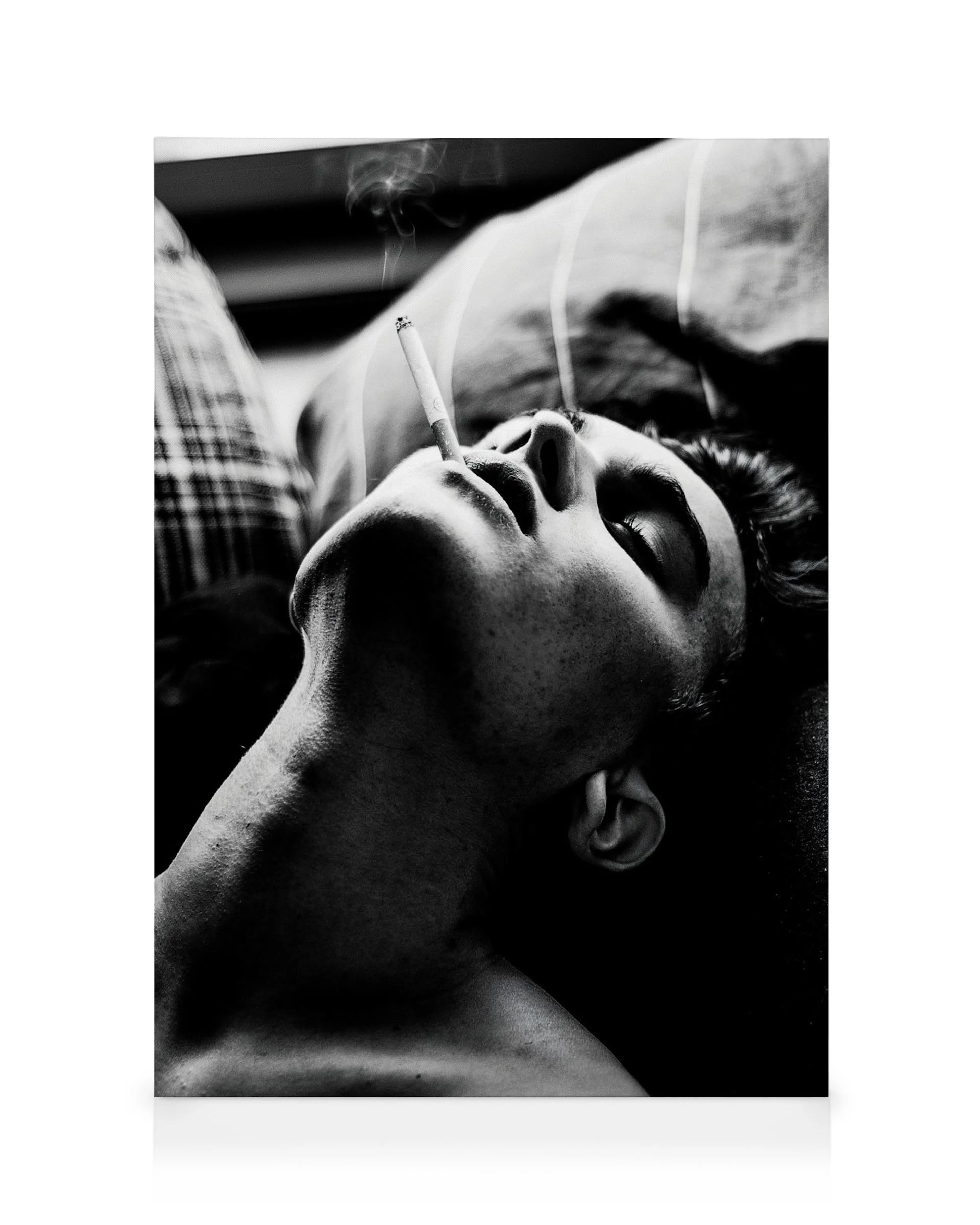 Black and white canvas print of a person lying back, eyes closed, smoking a cigarette, smoke rising from lips.