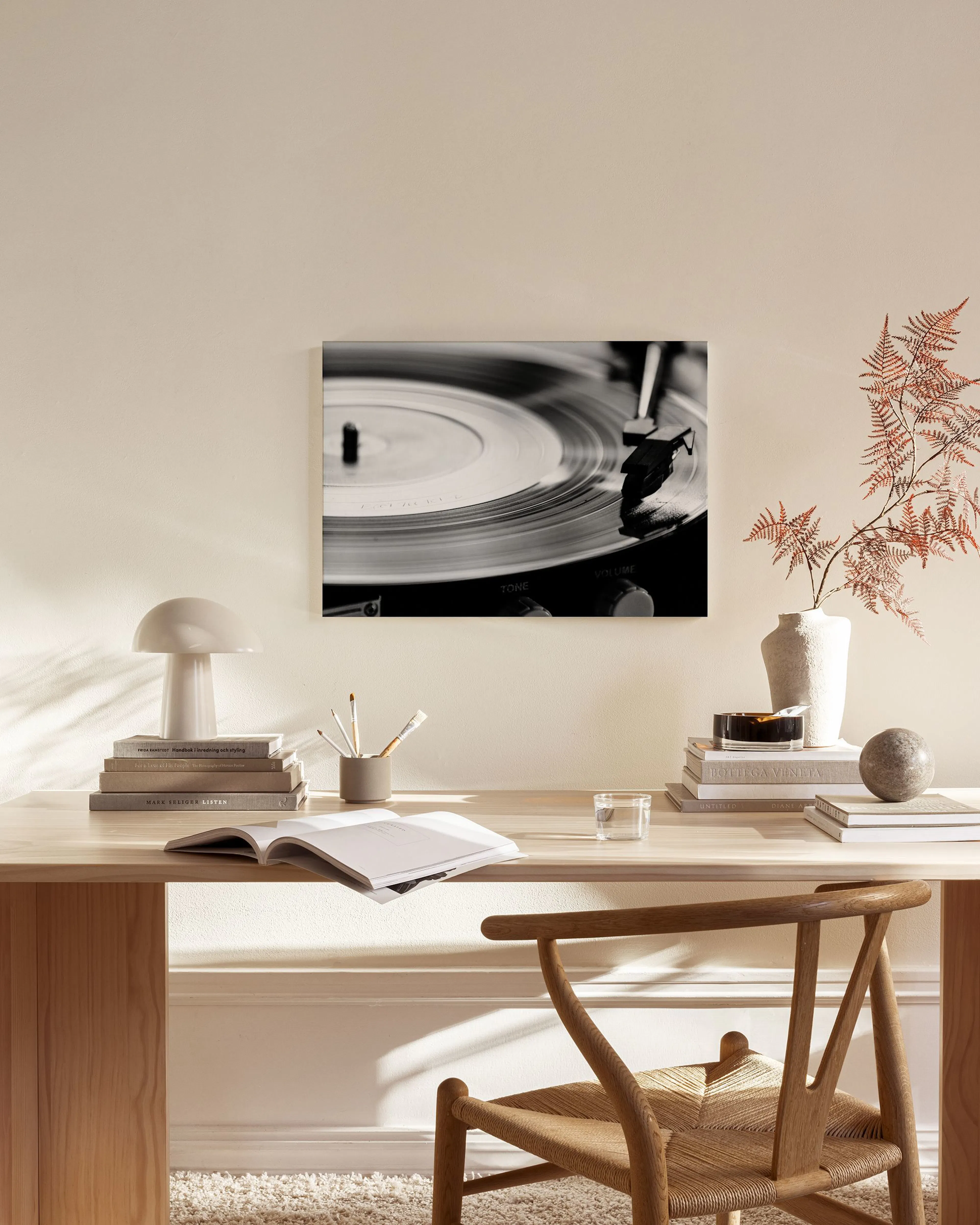 Svart-hvitt lerretsbilde av en platespiller, sentralt plassert på en beige vegg i en moderne stue.