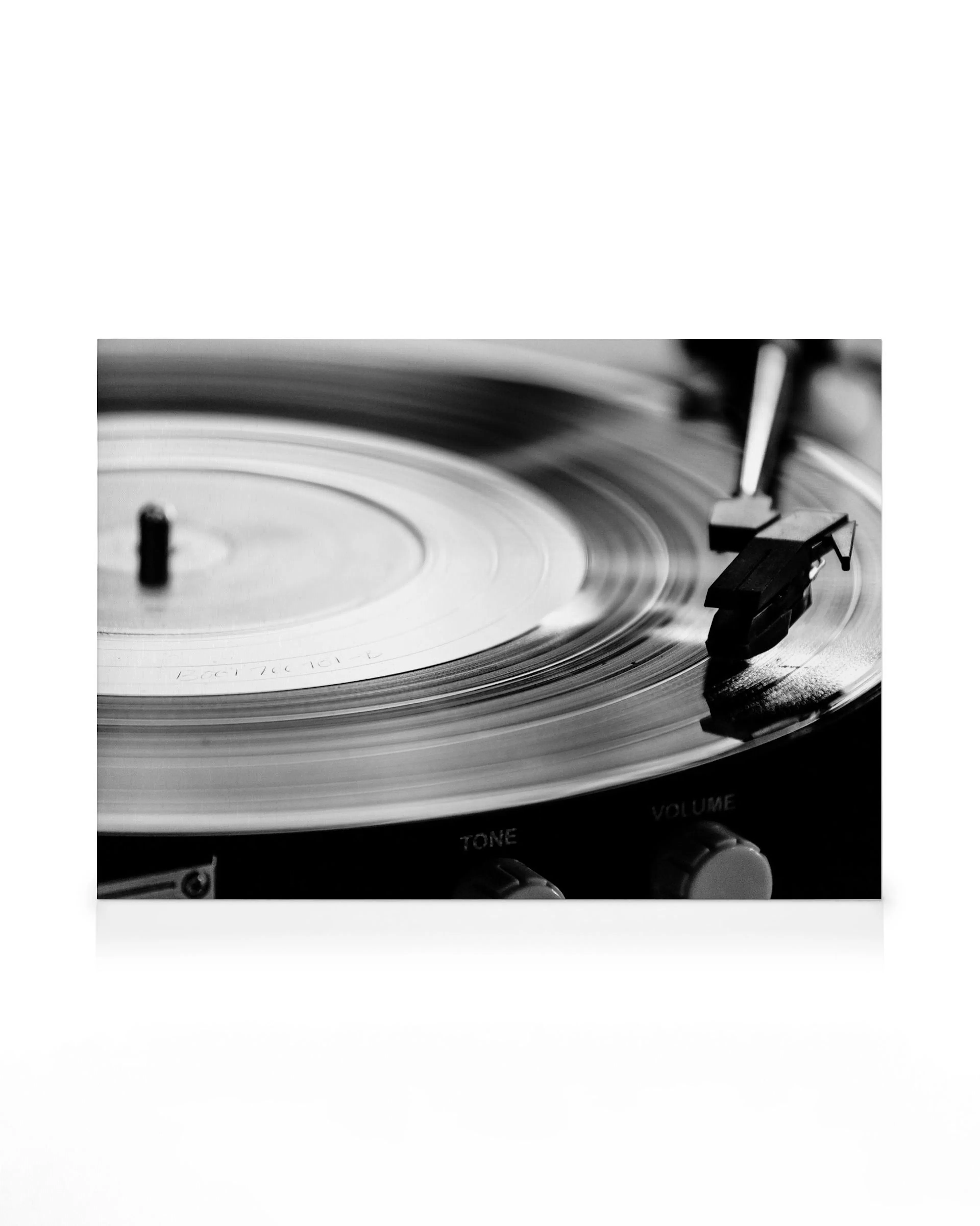 Giradischi vintage in bianco e nero con disco in vinile in movimento, puntina sul disco, pulsanti tono e volume.