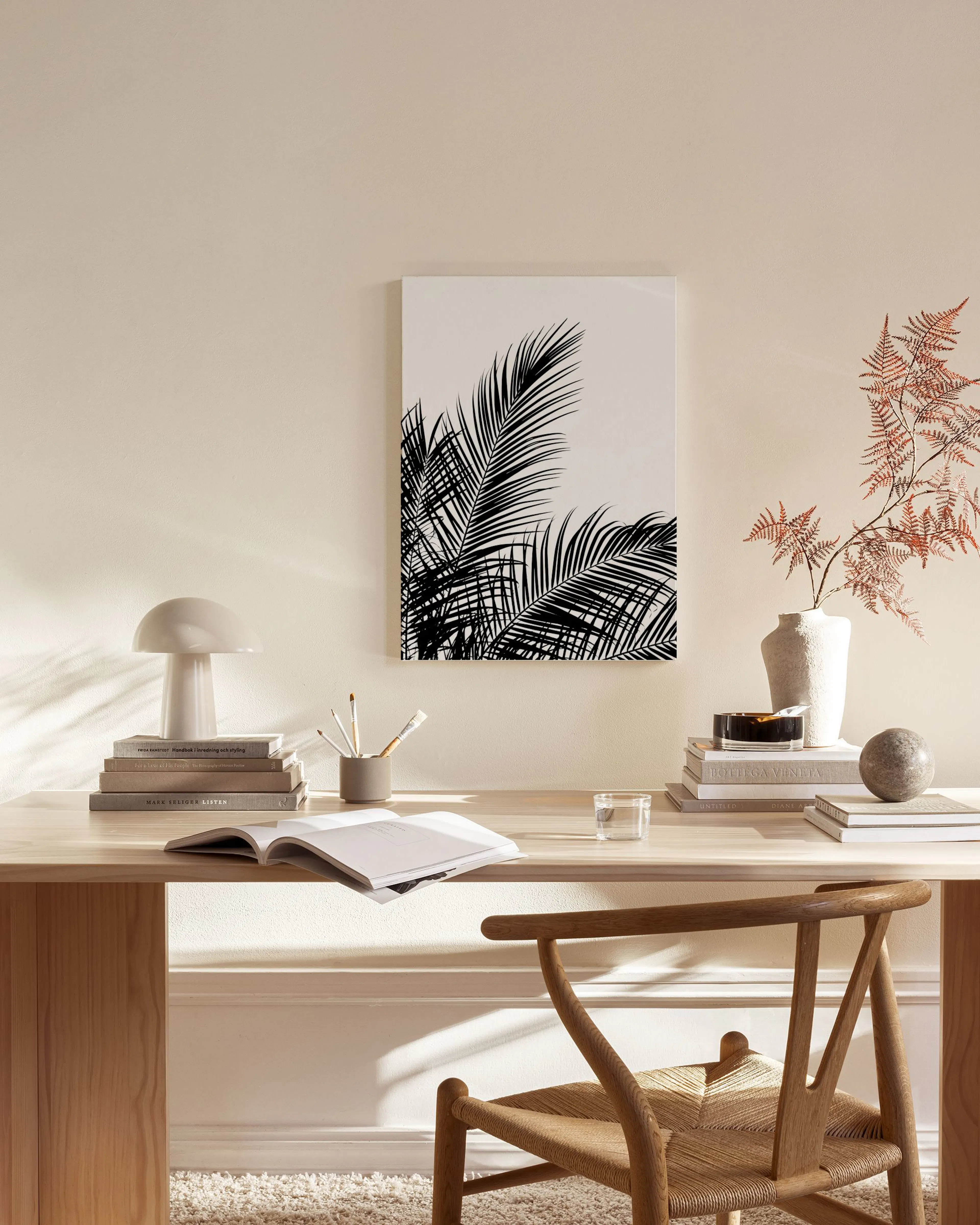Black and white palm leaves canvas print hanging above a console table in a minimalist living room.