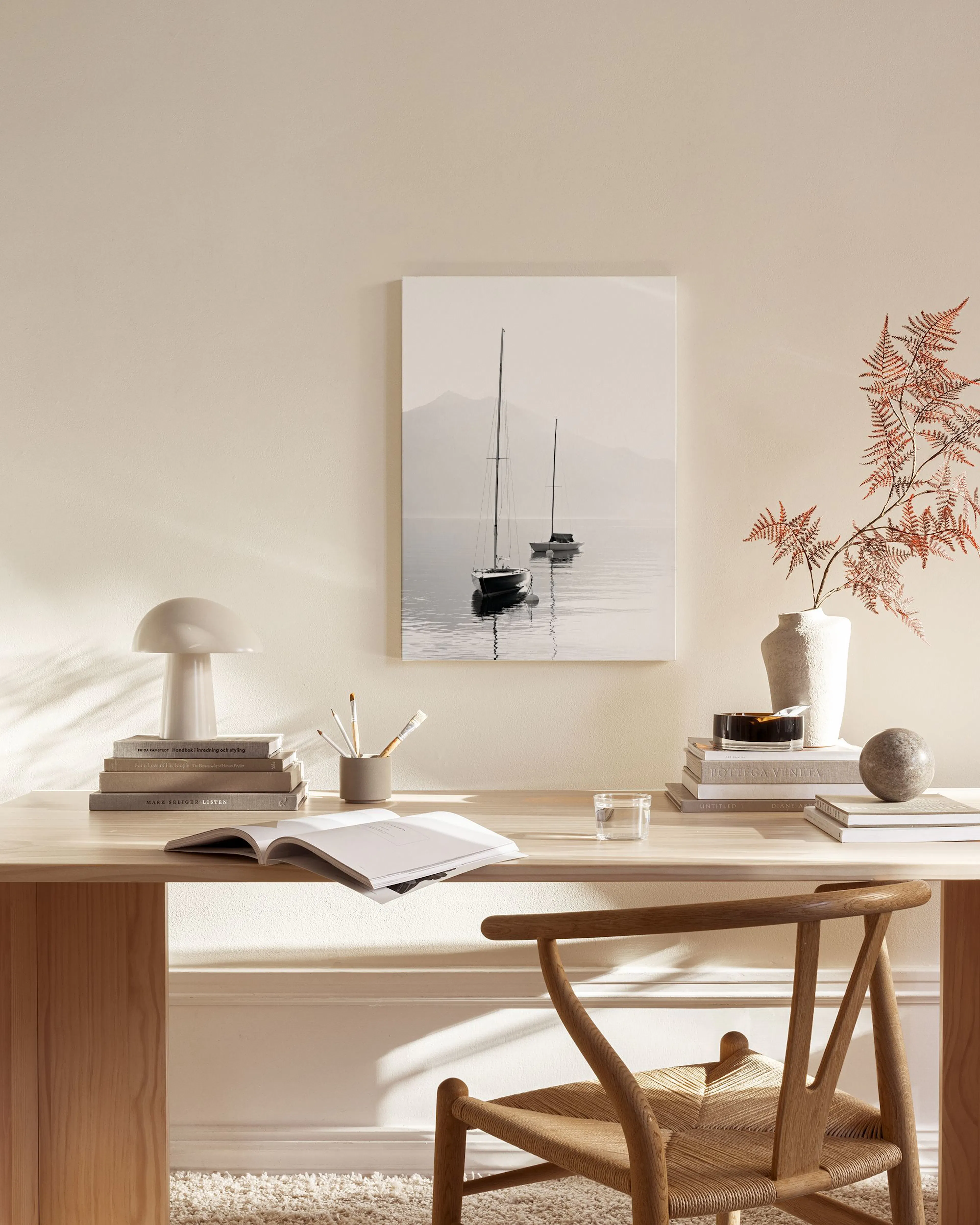 Leinwandbild mit zwei Segelbooten auf einem See vor Bergen, hängt in einem modernen Wohnzimmer über einem Sideboard.