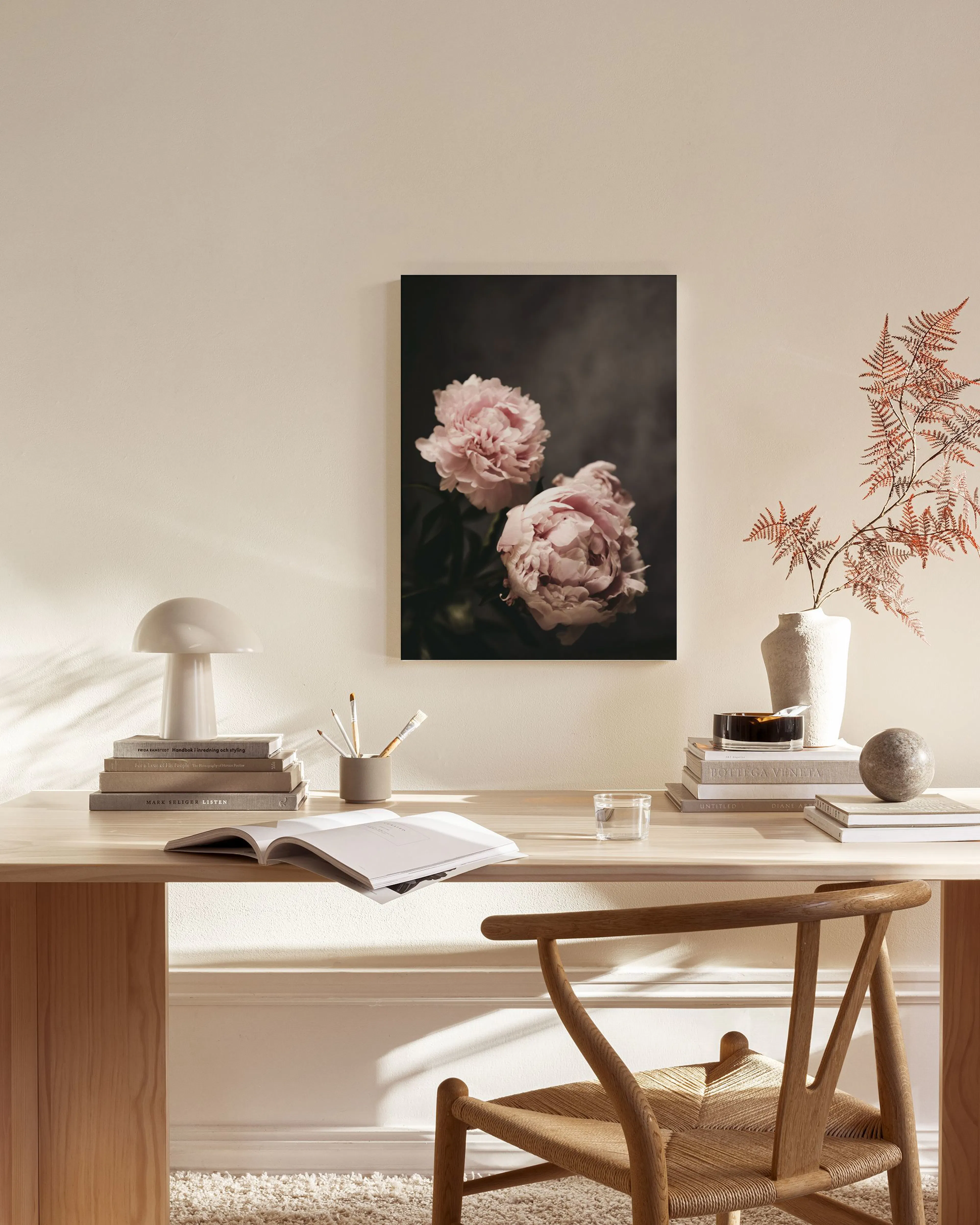 Leinwandbild mit zwei rosafarbenen Pfingstrosen auf dunklem Grund, hängend in einem stilvollen Wohnzimmer.