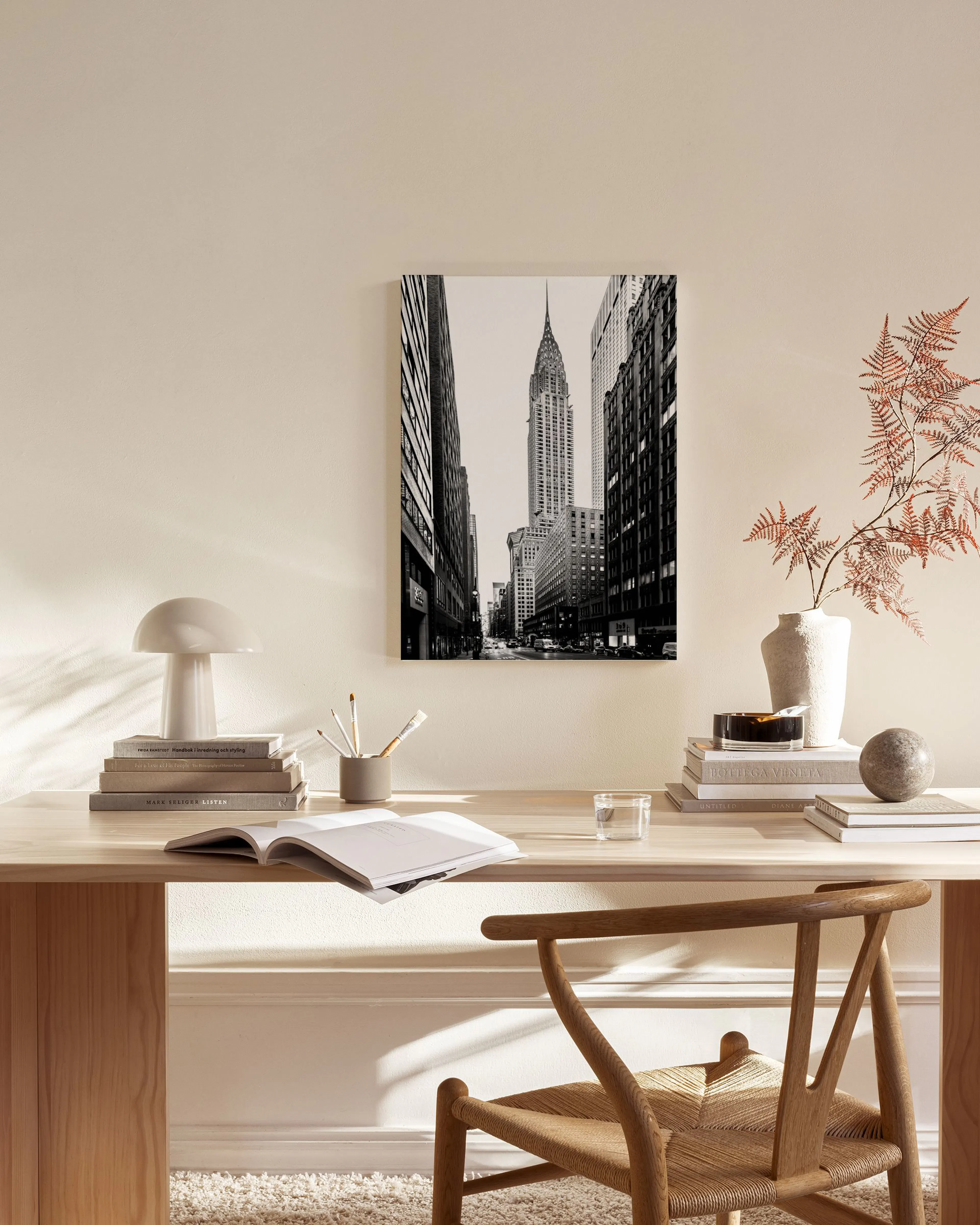 Czarno-biały obraz na płótnie z widokiem na wieżowiec Chrysler Building na tle innych budynków, zawieszony w jasnym salonie.