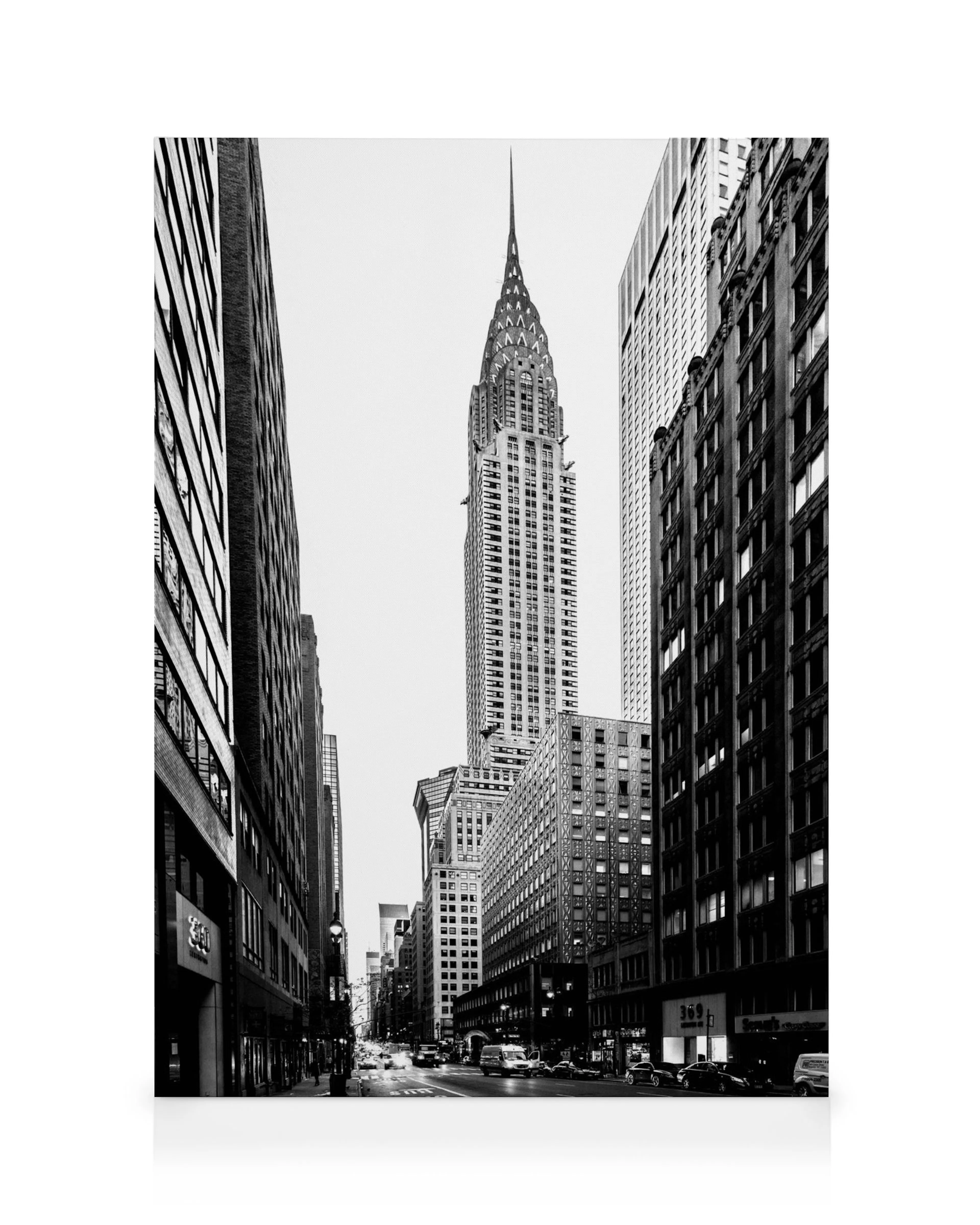 Czarno-białe zdjęcie Chrysler Building w centrum Nowego Jorku, otoczonego ulicami i budynkami, w perspektywie miejskiej.