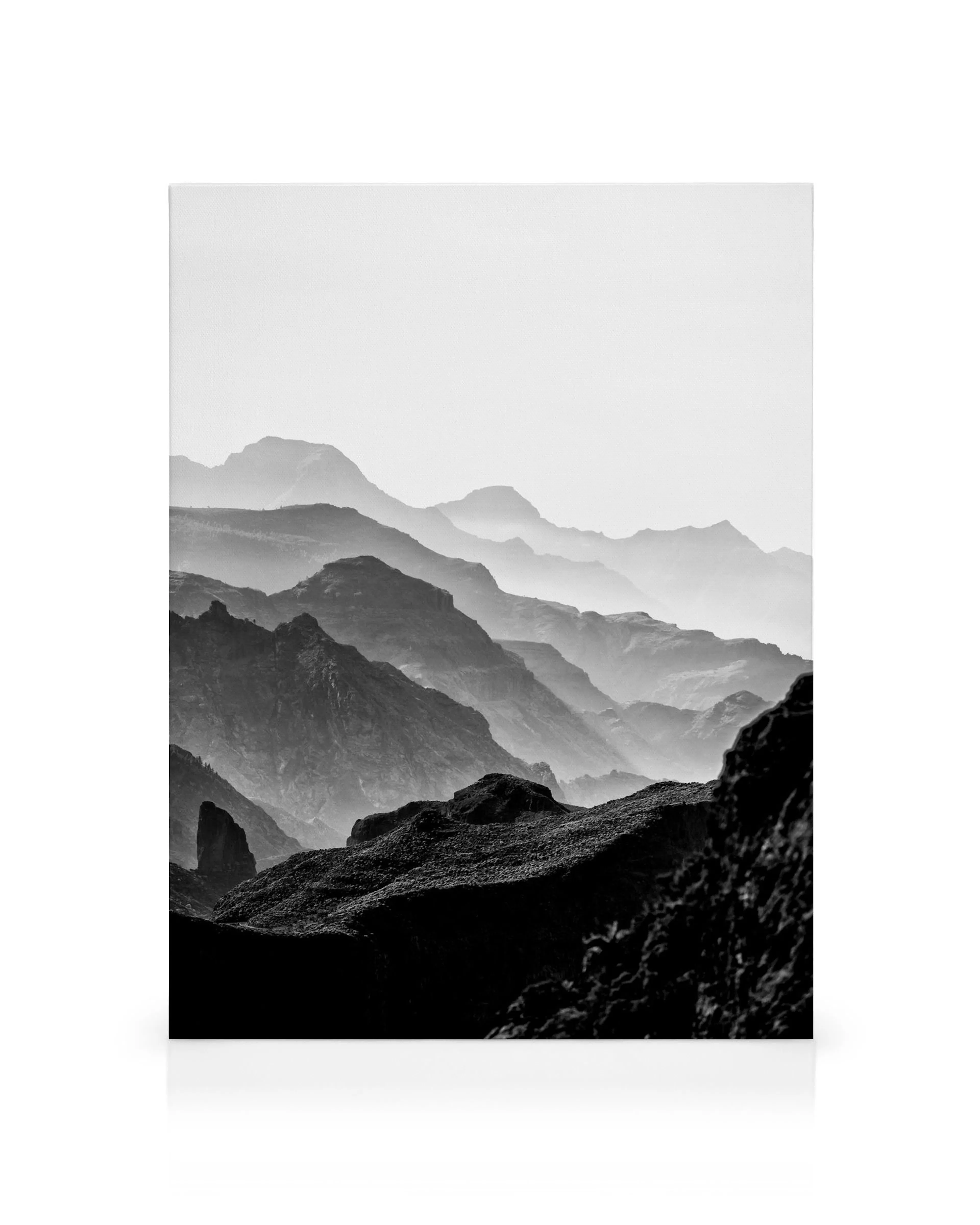 Toile noire et blanche de montagnes rocheuses superposées avec cimes brumeuses et textures rugueuses