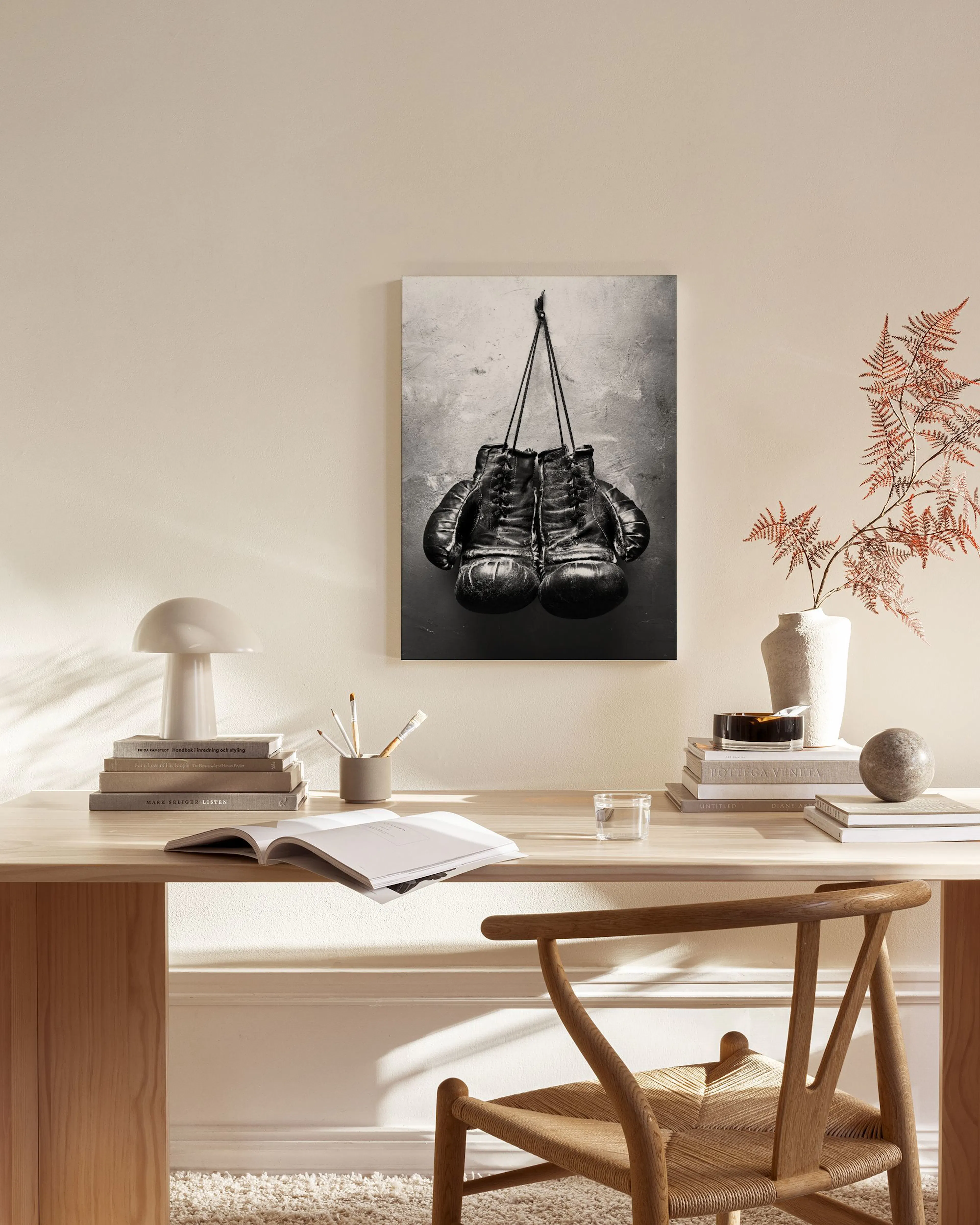 A black and white canvas print of vintage boxing gloves hanging, displayed in a modern living room.