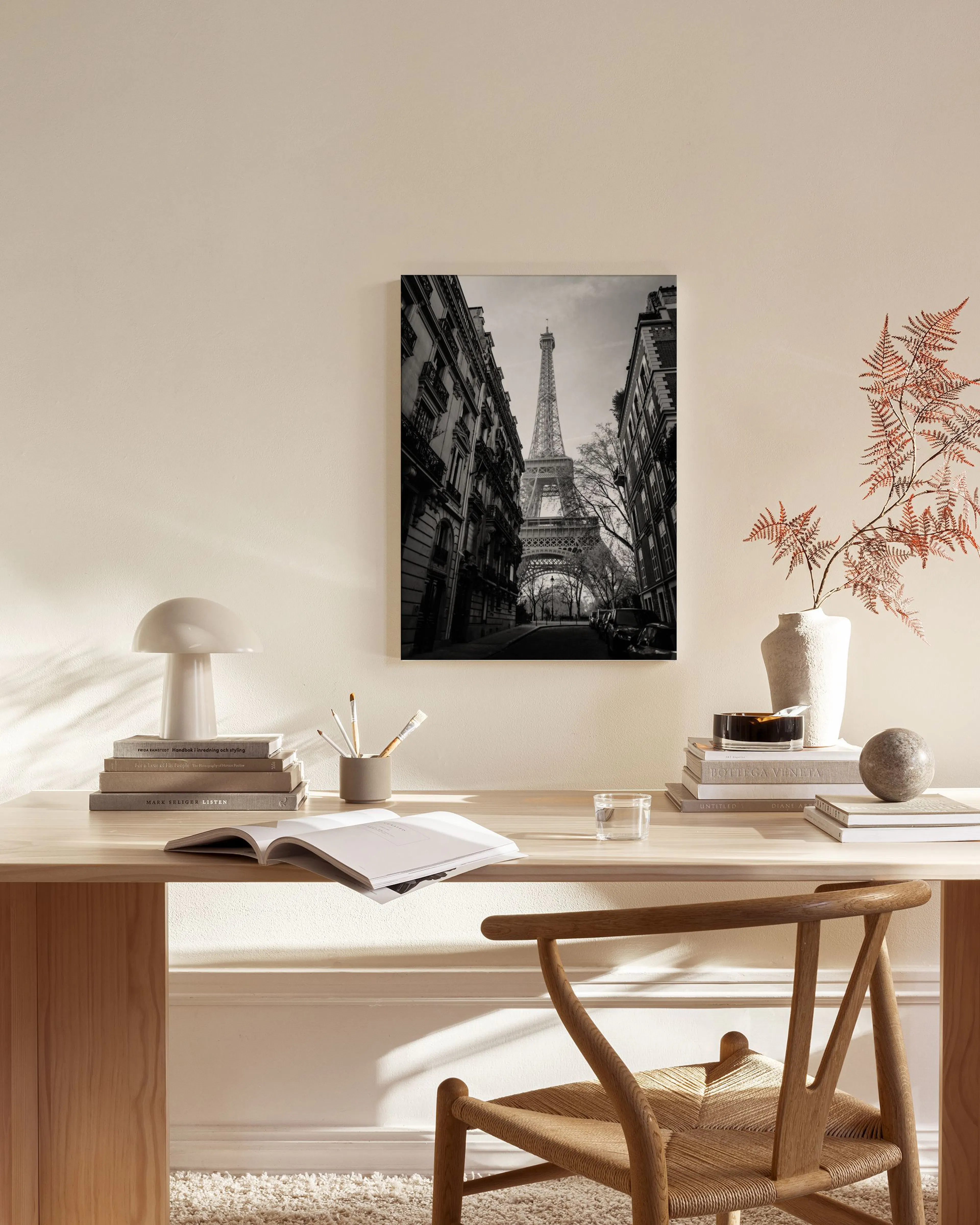 Zwart-wit canvas van de Eiffeltoren in Parijs, hangend boven een houten dressoir in een moderne woonkamer.