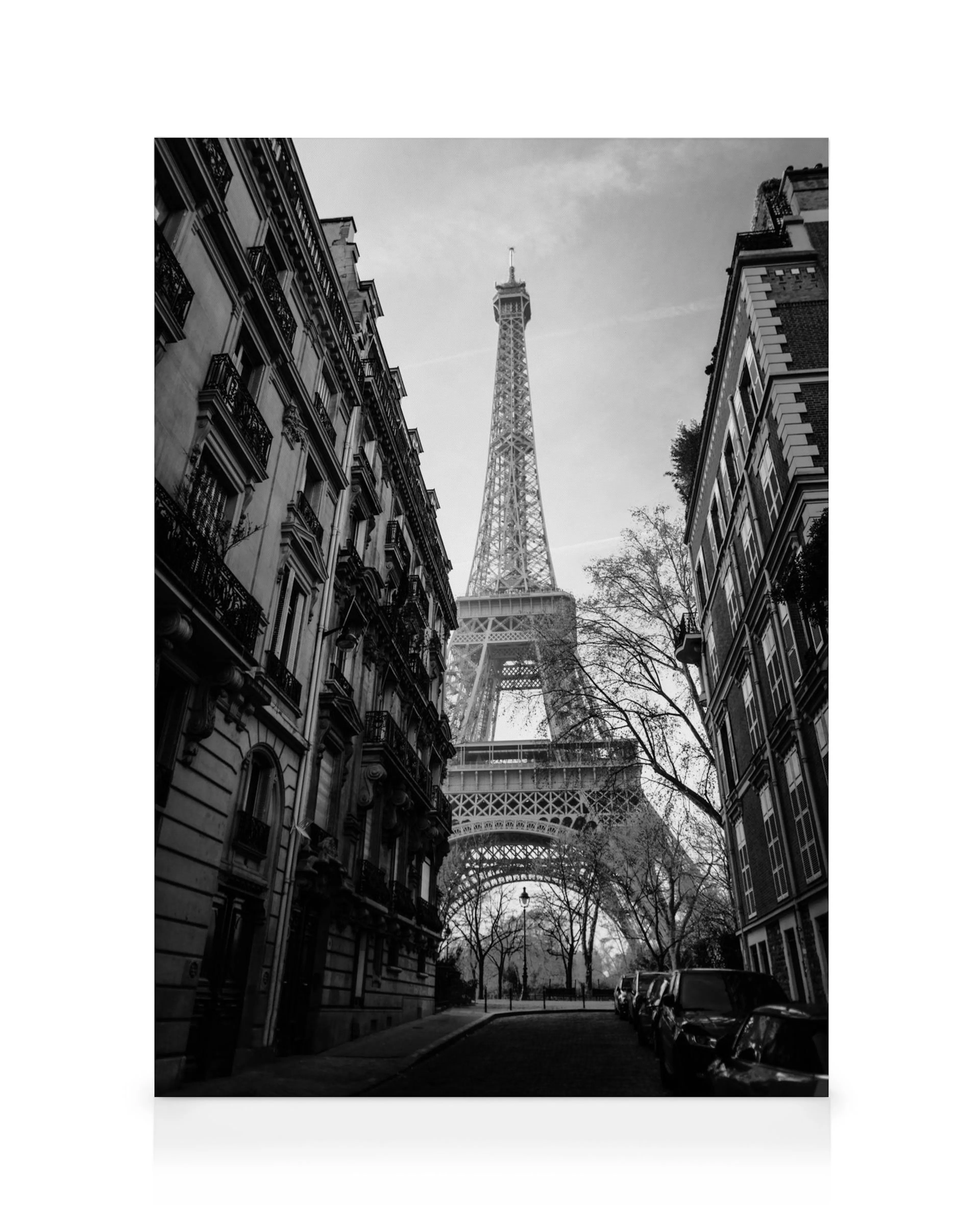 Black and white canvas print of the Eiffel Tower framed by Parisian buildings and a street leading towards it.