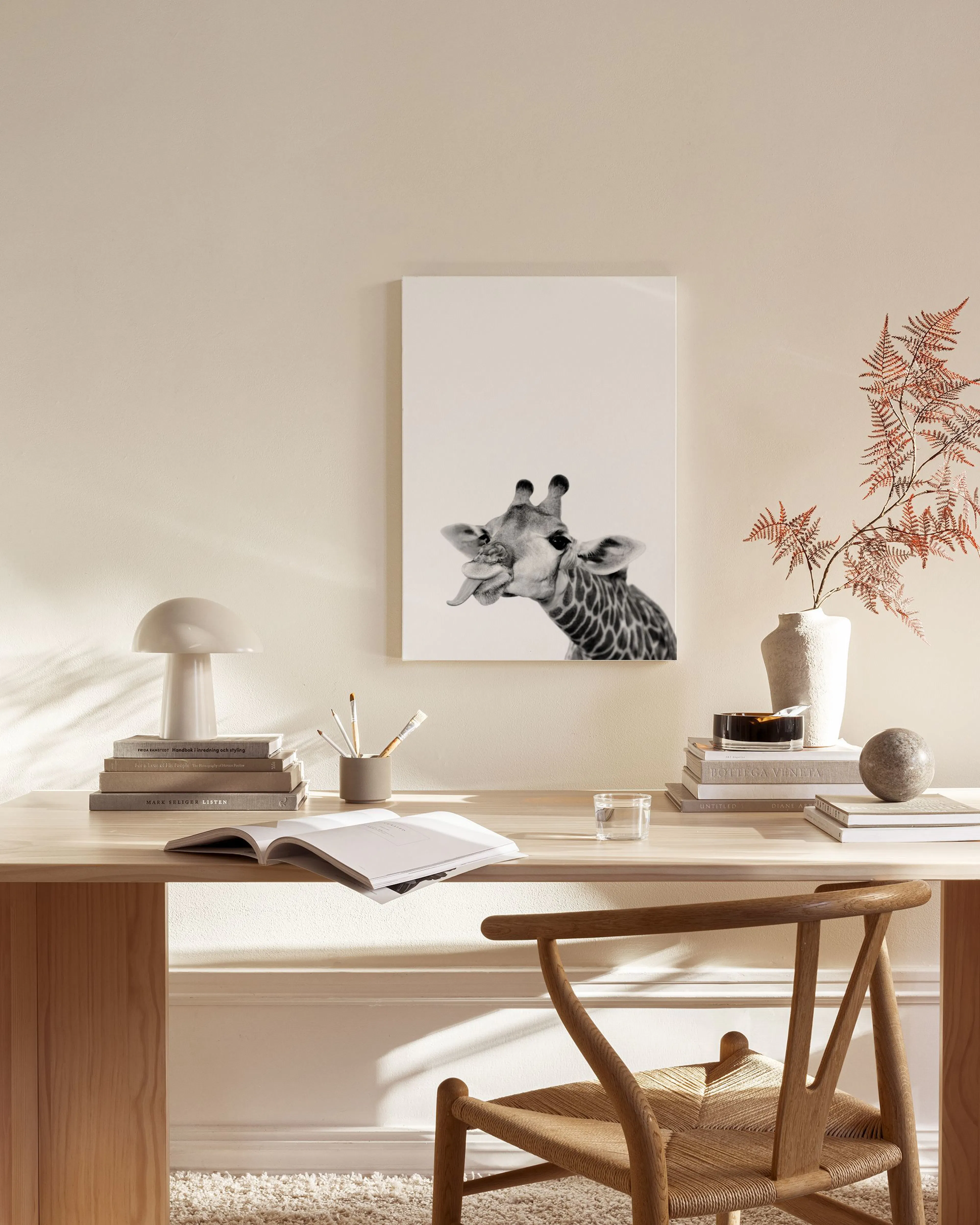 Black and white canvas print of a giraffe sticking out its tongue, displayed on a light wall in a minimalist living room.