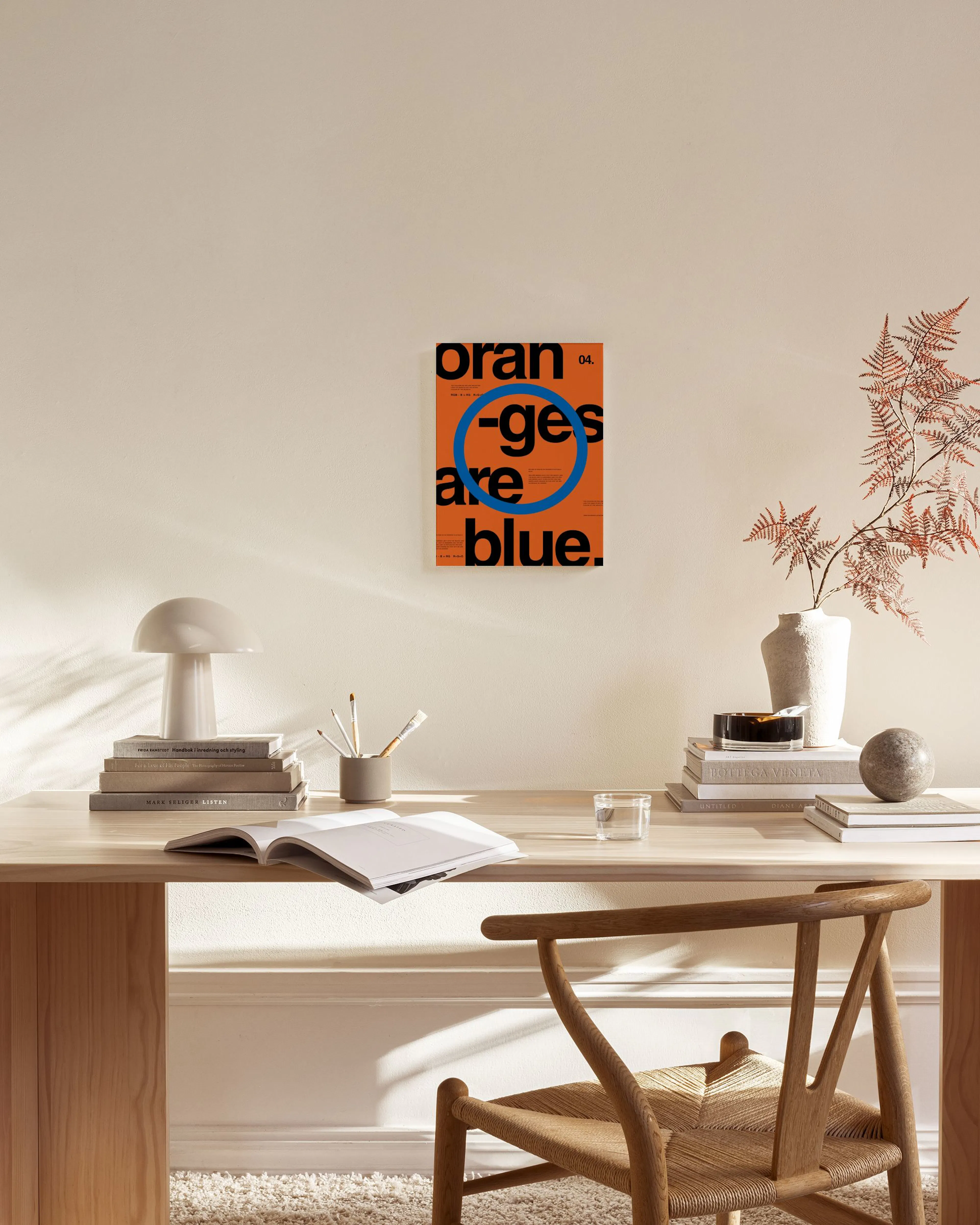 Toile de style moderne affichant ORANGES ARE BLUE en noir sur fond orange, avec cercle bleu, dans un salon lumineux.