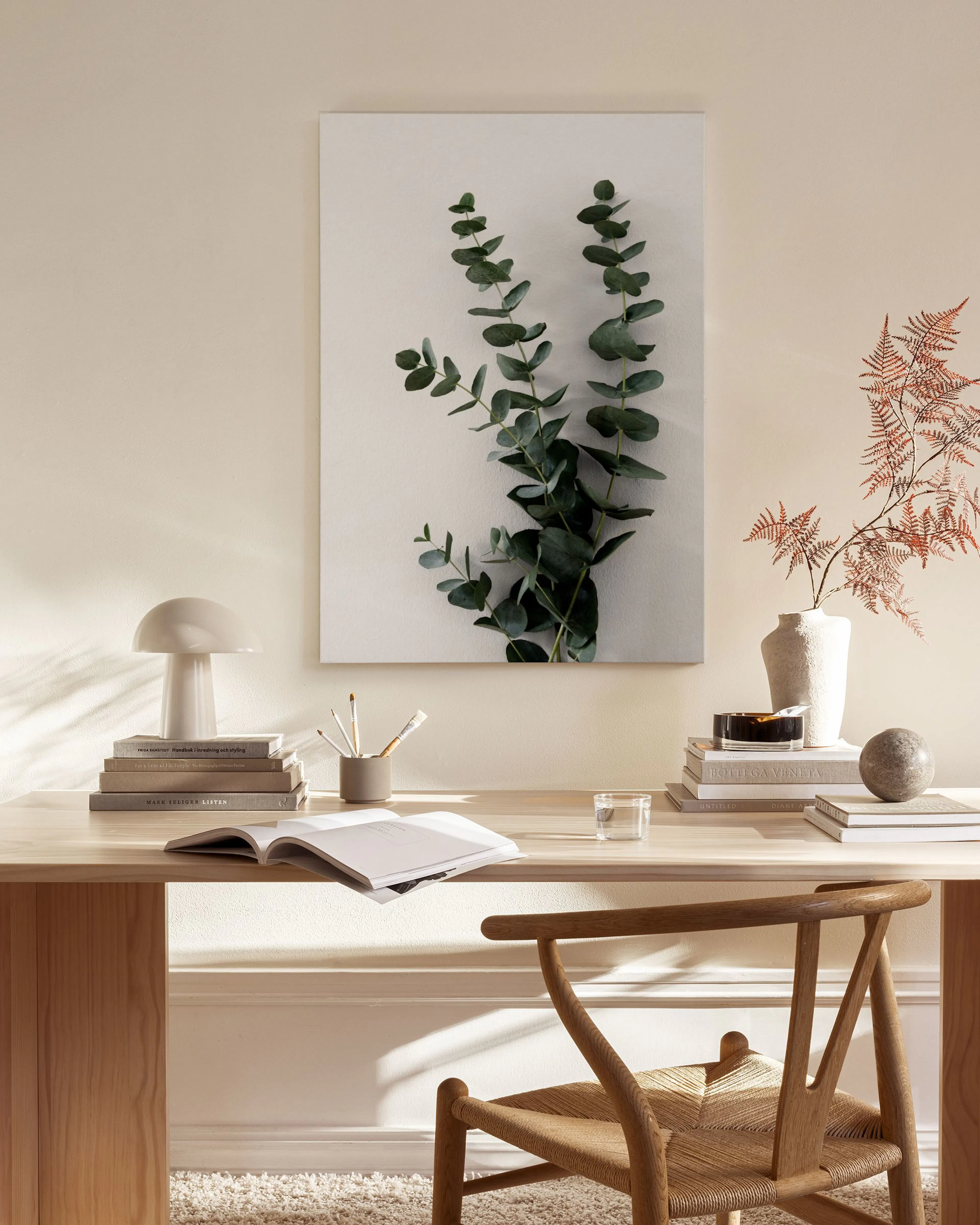 Toile murale deucalyptus suspendue au-dessus dun banc en bois dans un salon lumineux et minimaliste.
