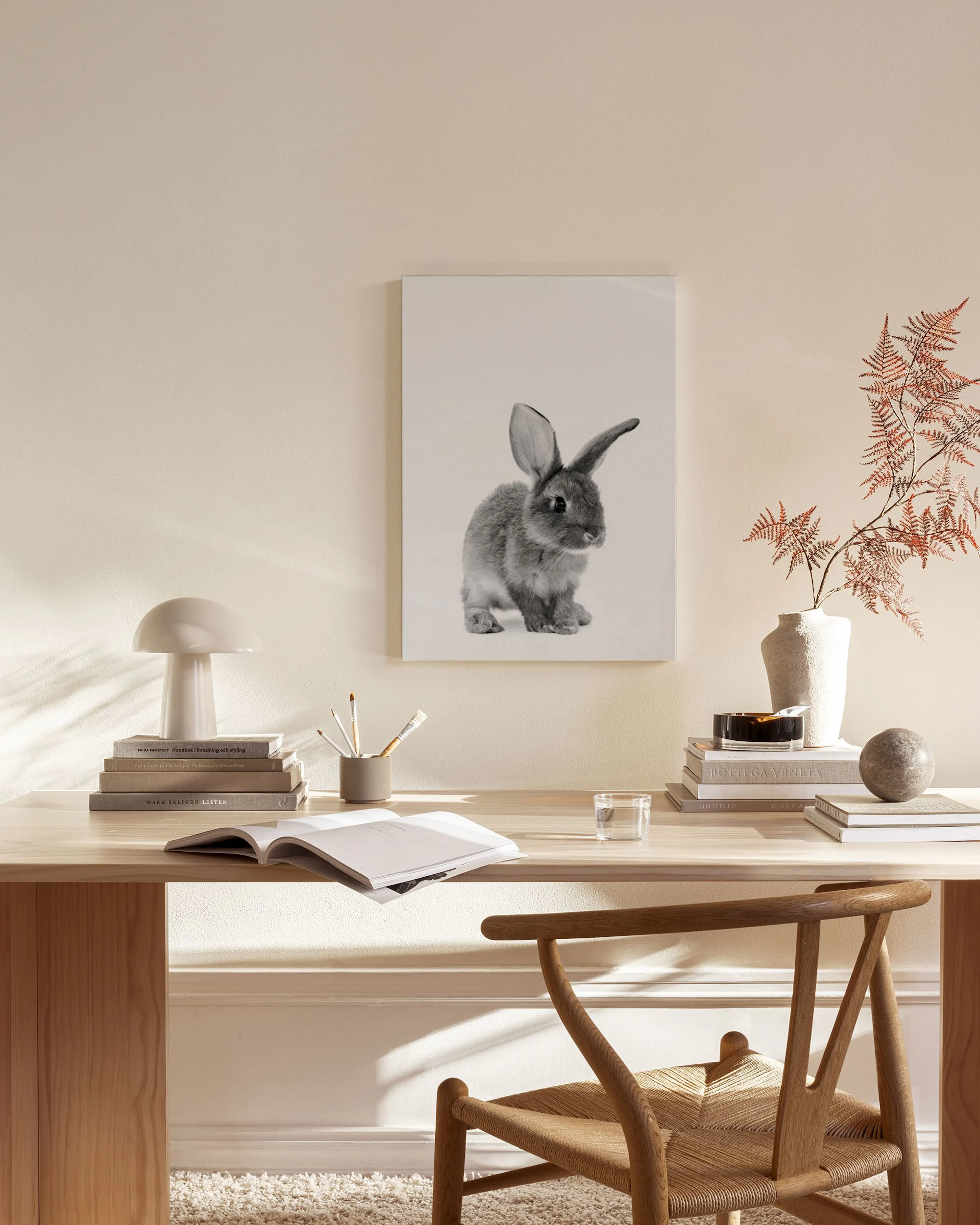 A black and white canvas print of a cute baby rabbit on a light background, hanging in a minimalist living room.