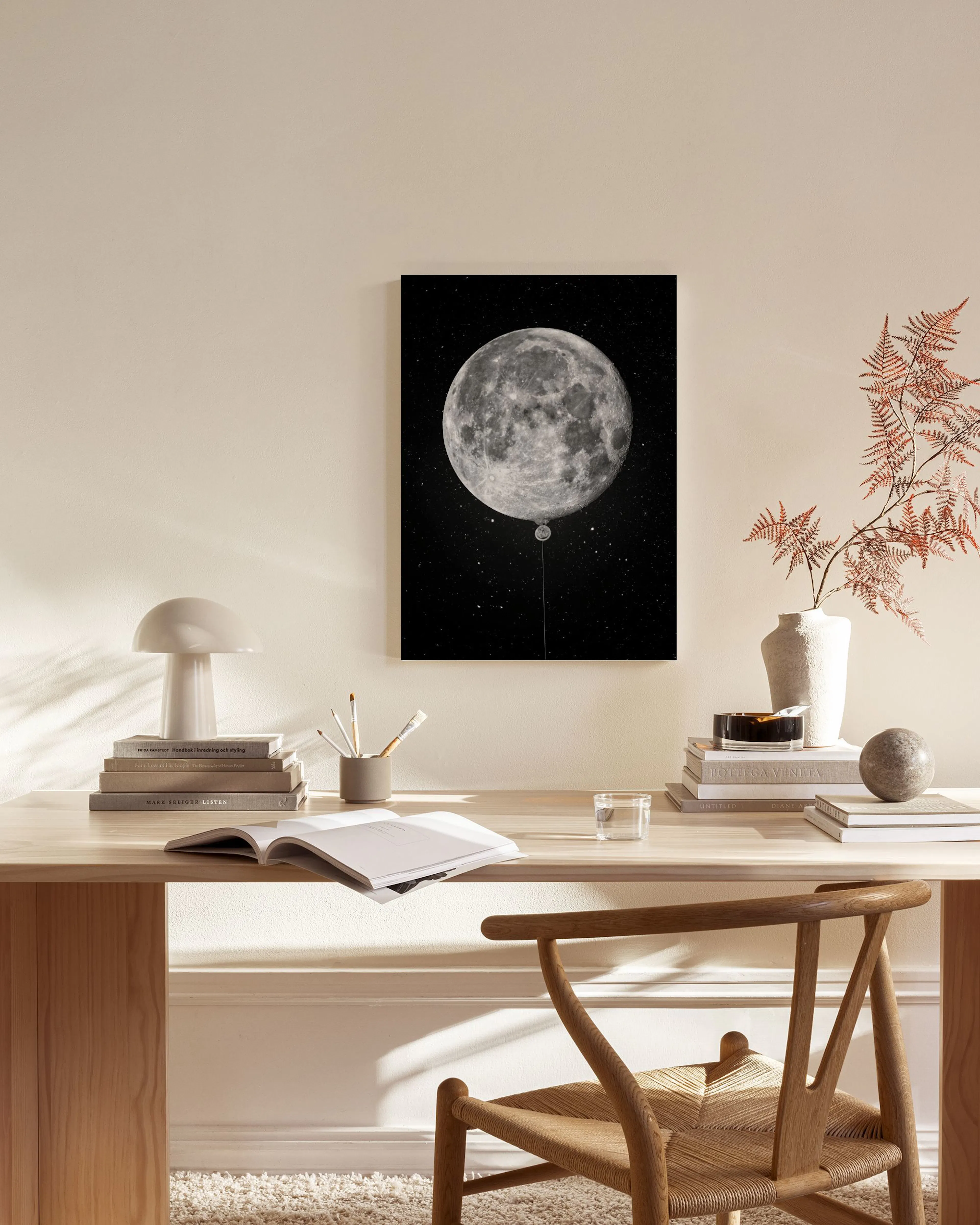 Lienzo de la luna como un globo oscuro, colgado en una sala de estar moderna sobre un mueble bajo con una lámpara.