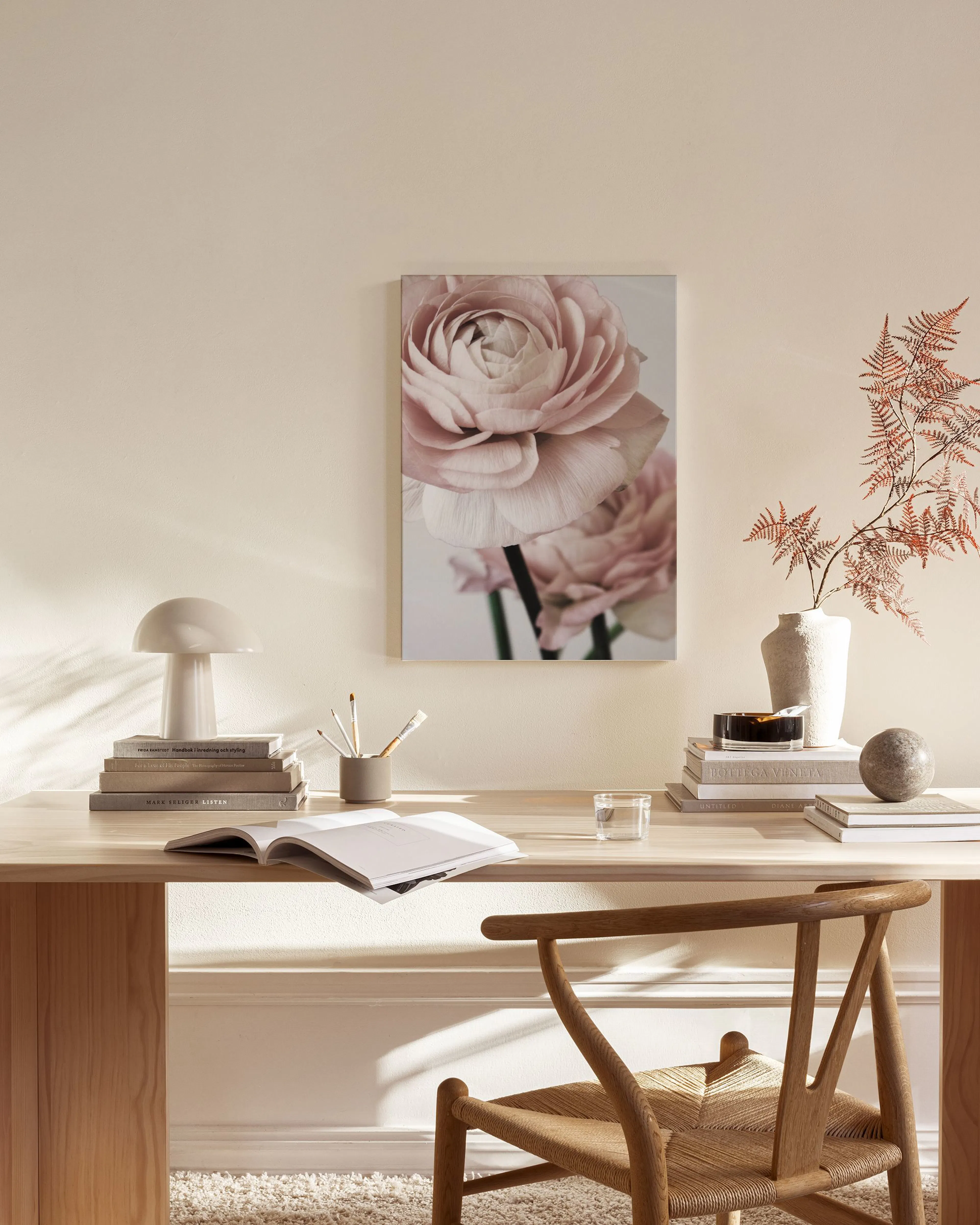 Canvastavla med rosa ranunkel hängande i ett ljust vardagsrum med trädetaljer och en glasbord.