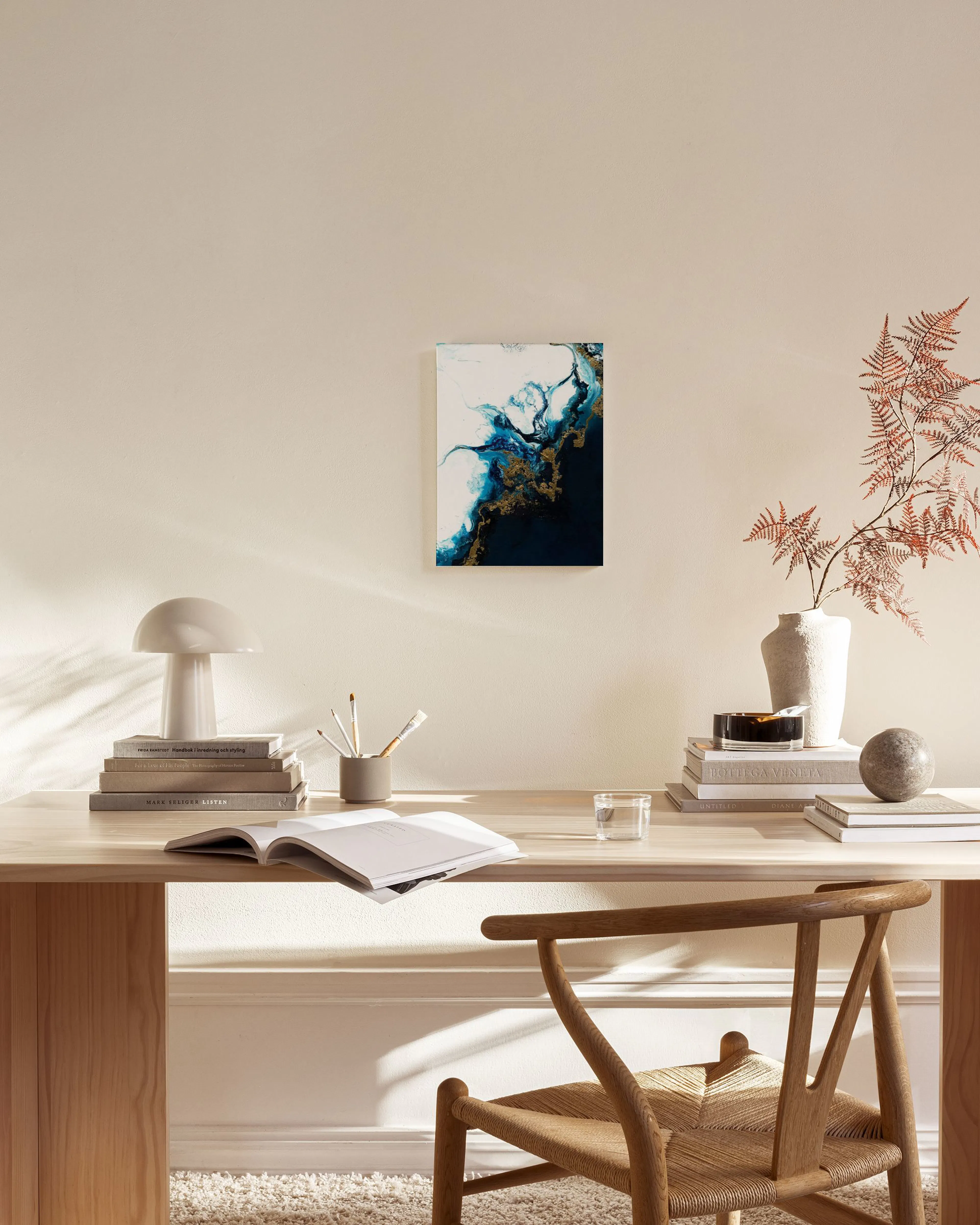 Abstract dark blue, white, and gold fluid art print hanging in a modern living room above a wooden console.