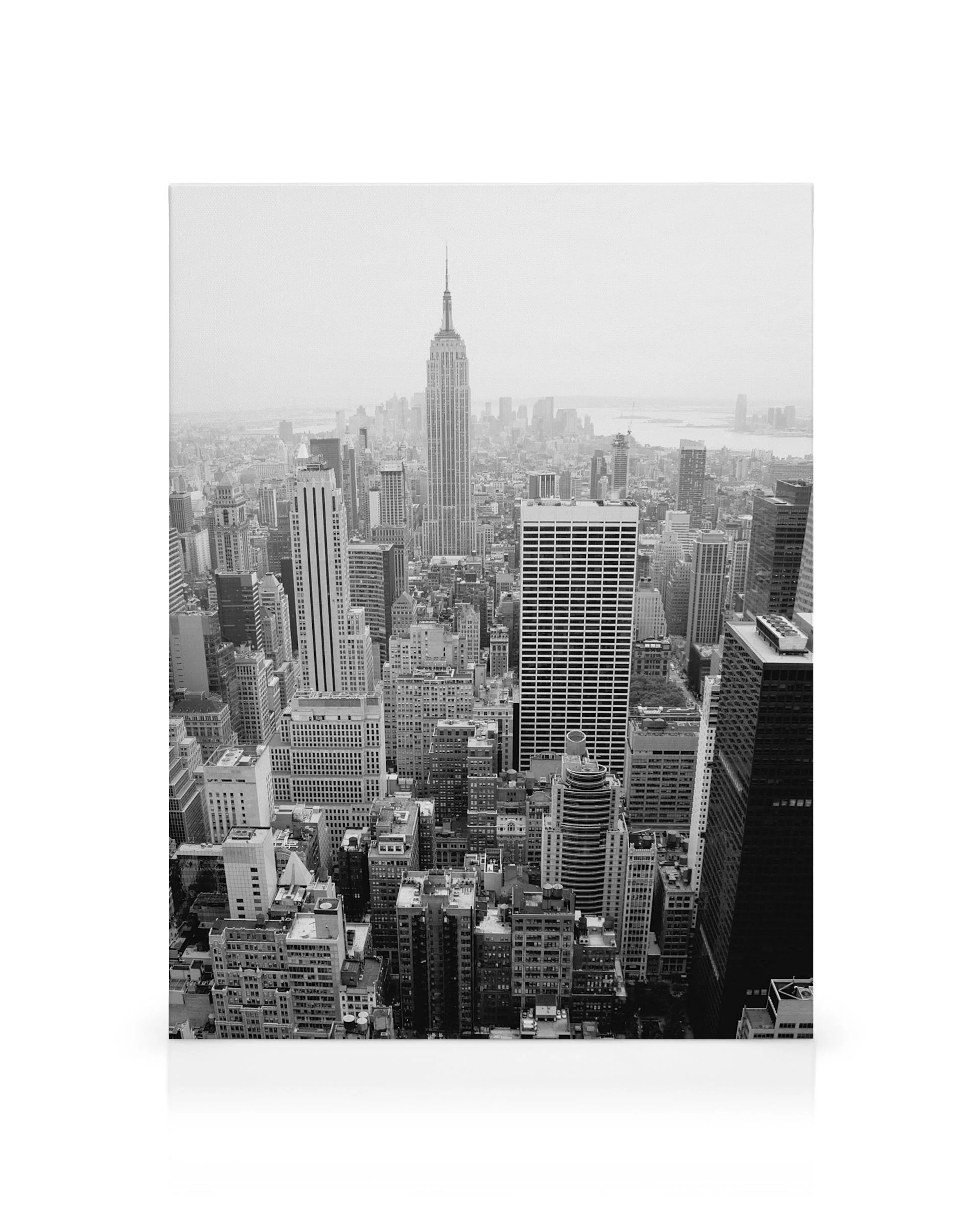 Black and white New York City canvas print with tall buildings and a river under a cloudy sky.