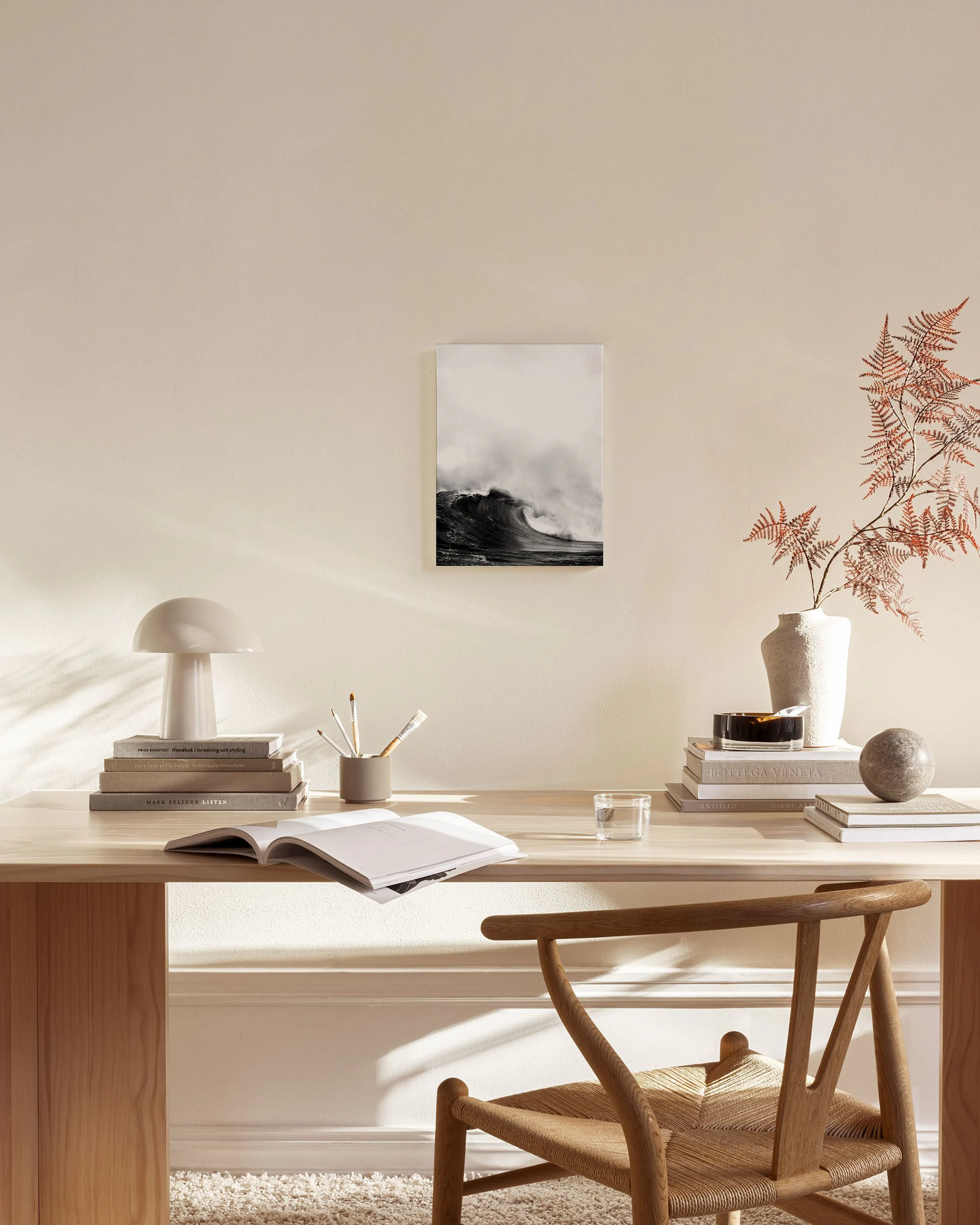 Black and white canvas print of a large, powerful ocean wave crashing, displayed above a console table in a minimalist living ro