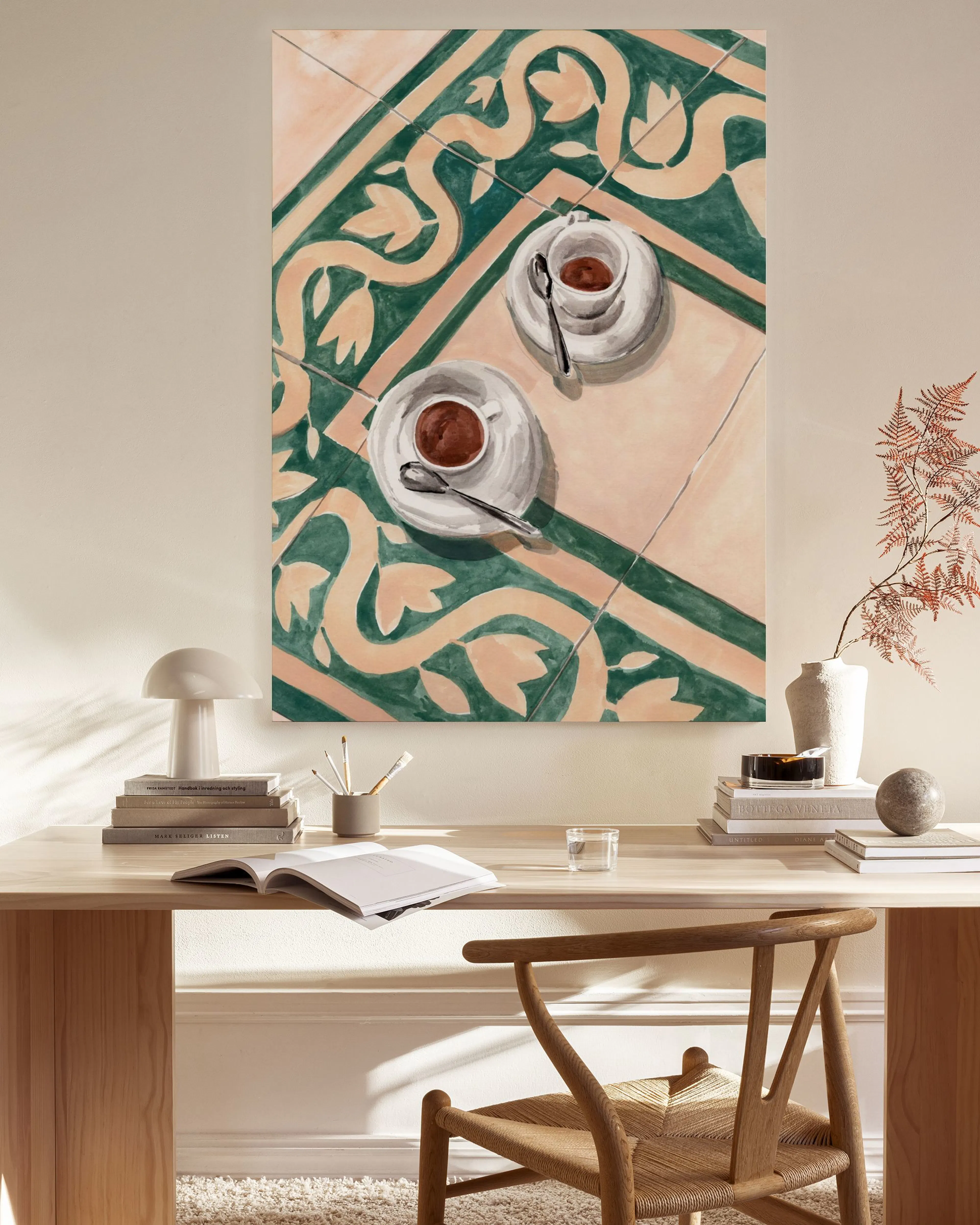 A canvas print of two espresso cups and saucers on a patterned tile table with green and beige designs.