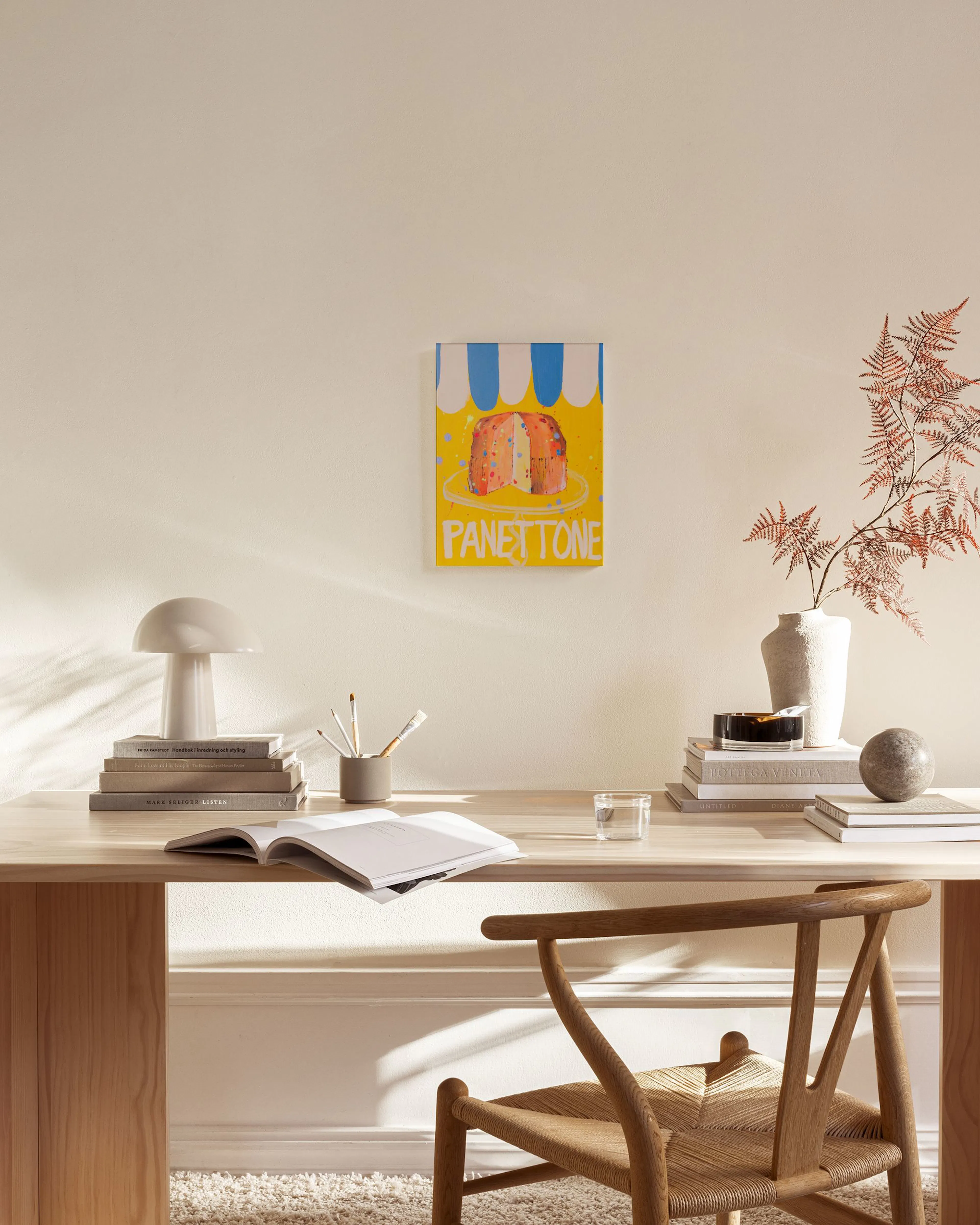 A vibrant pop art style canvas print of a panettone cake on a yellow background, hanging above a wooden console table in a minim