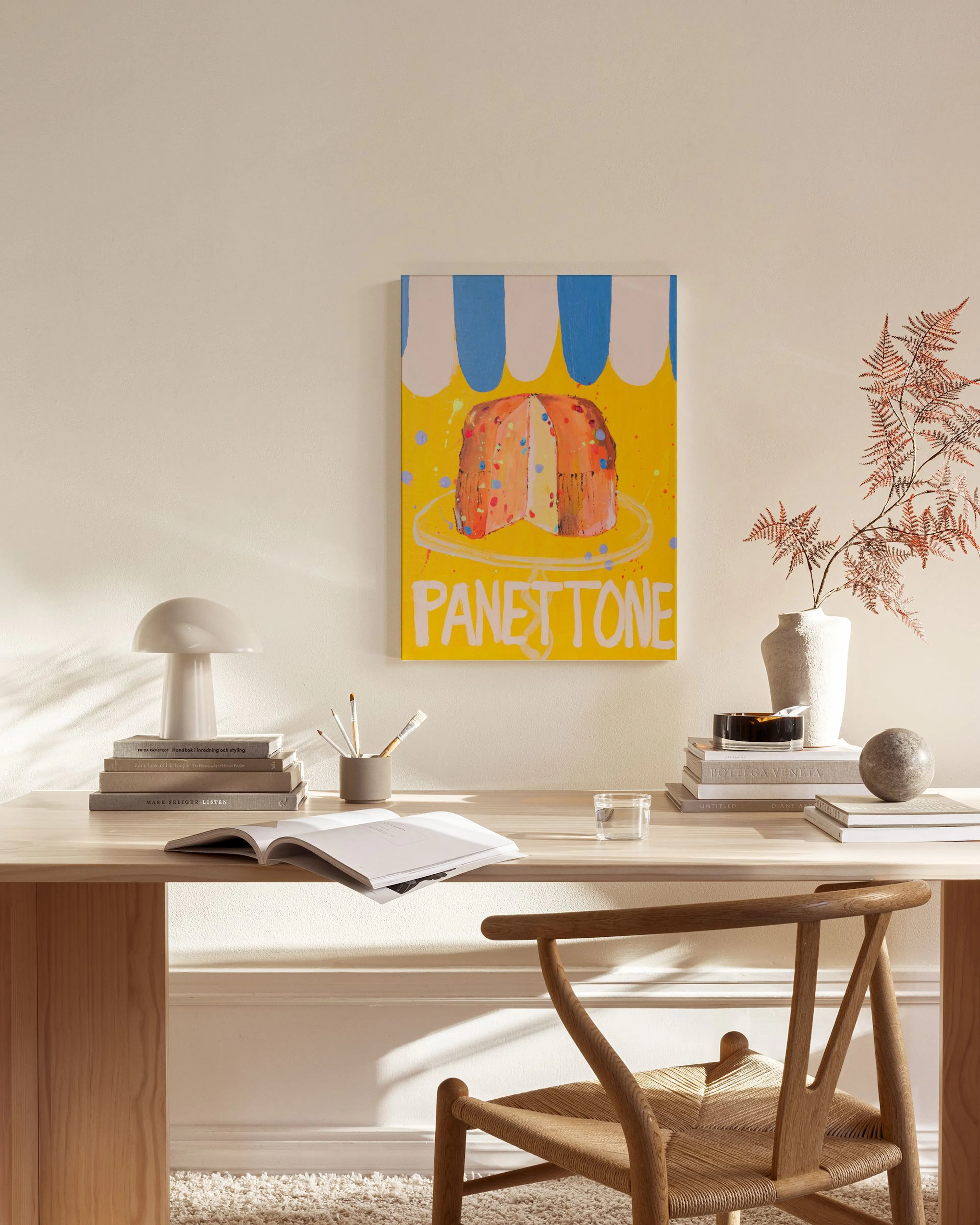 Stampa su tela con panettone su sfondo giallo, in un soggiorno moderno con poltrona in legno.