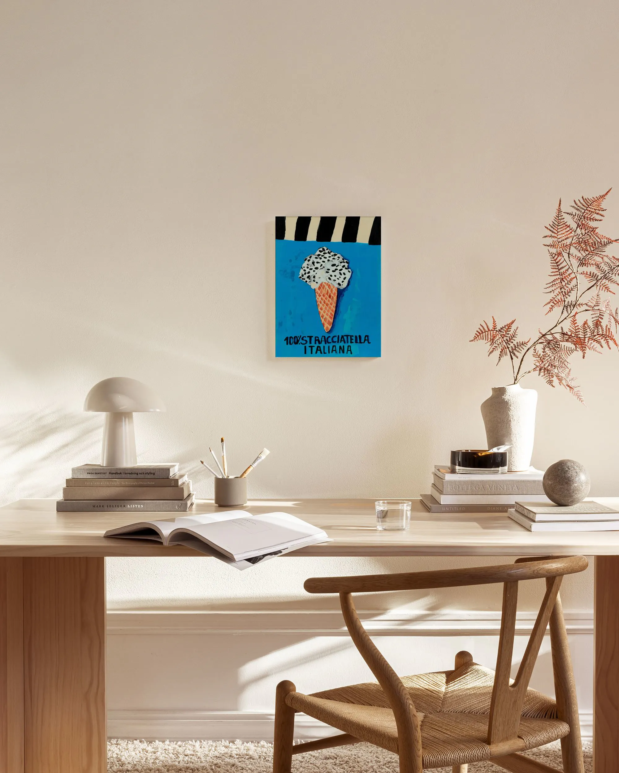Stampa su tela di un cono gelato stracciatella su sfondo blu, appesa in un moderno soggiorno con mobili in legno chiaro.