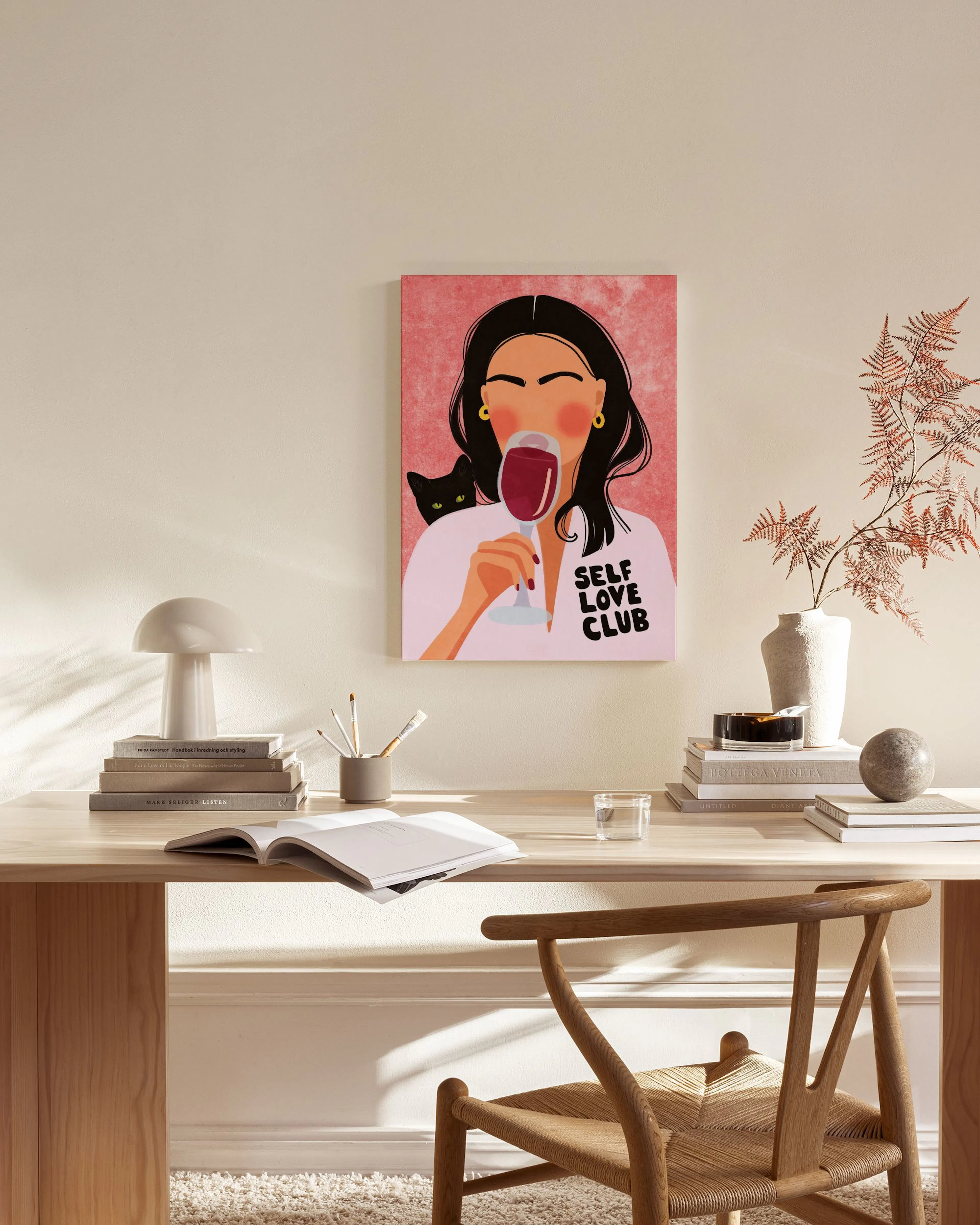 Obraz na płótnie z kobietą pijącą wino, z napisem Self Love Club i czarnym kotem, wiszący w salonie nad szafką.