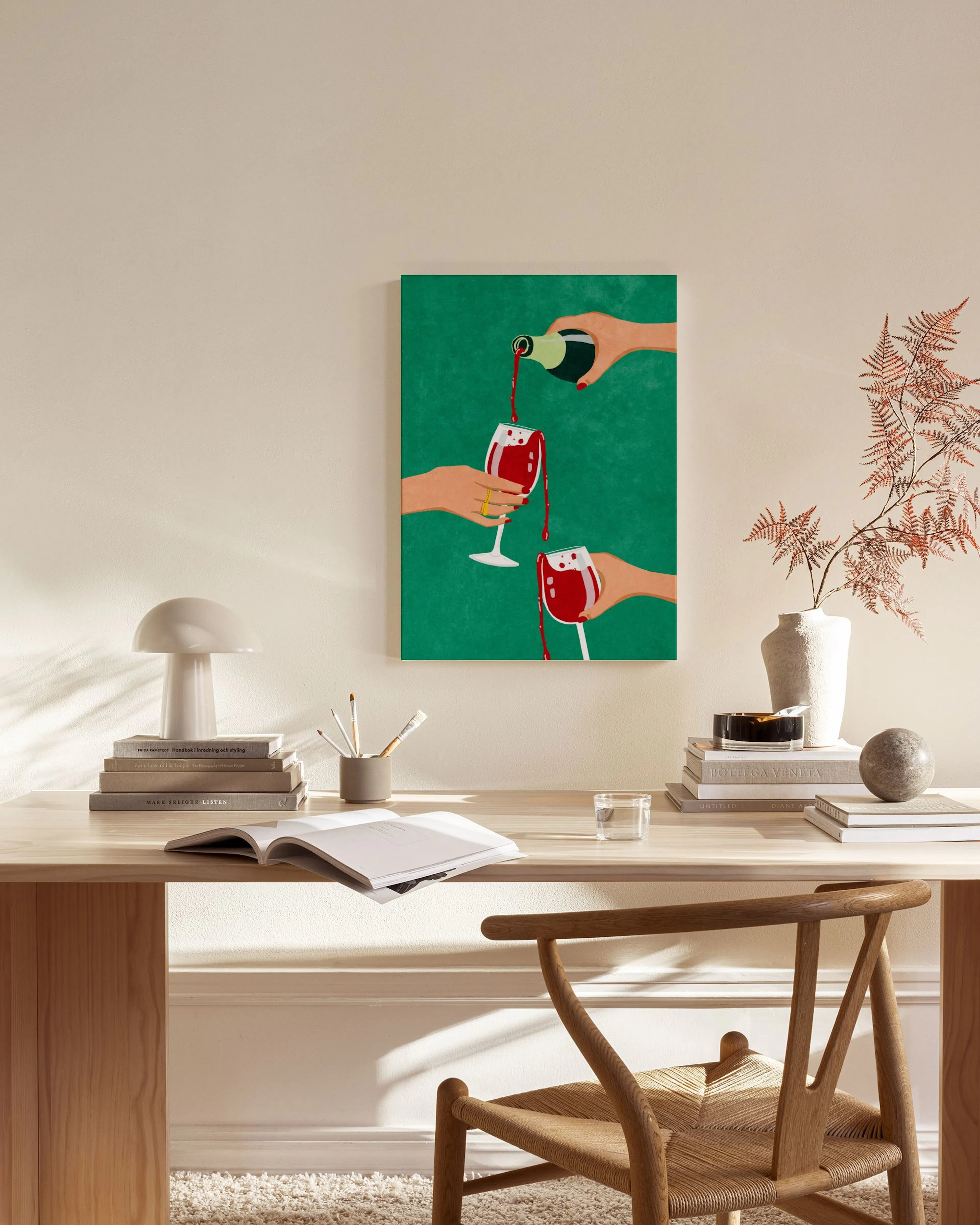 A canvas print of hands pouring and holding red wine glasses on a green background, displayed in a neutral-toned living room.