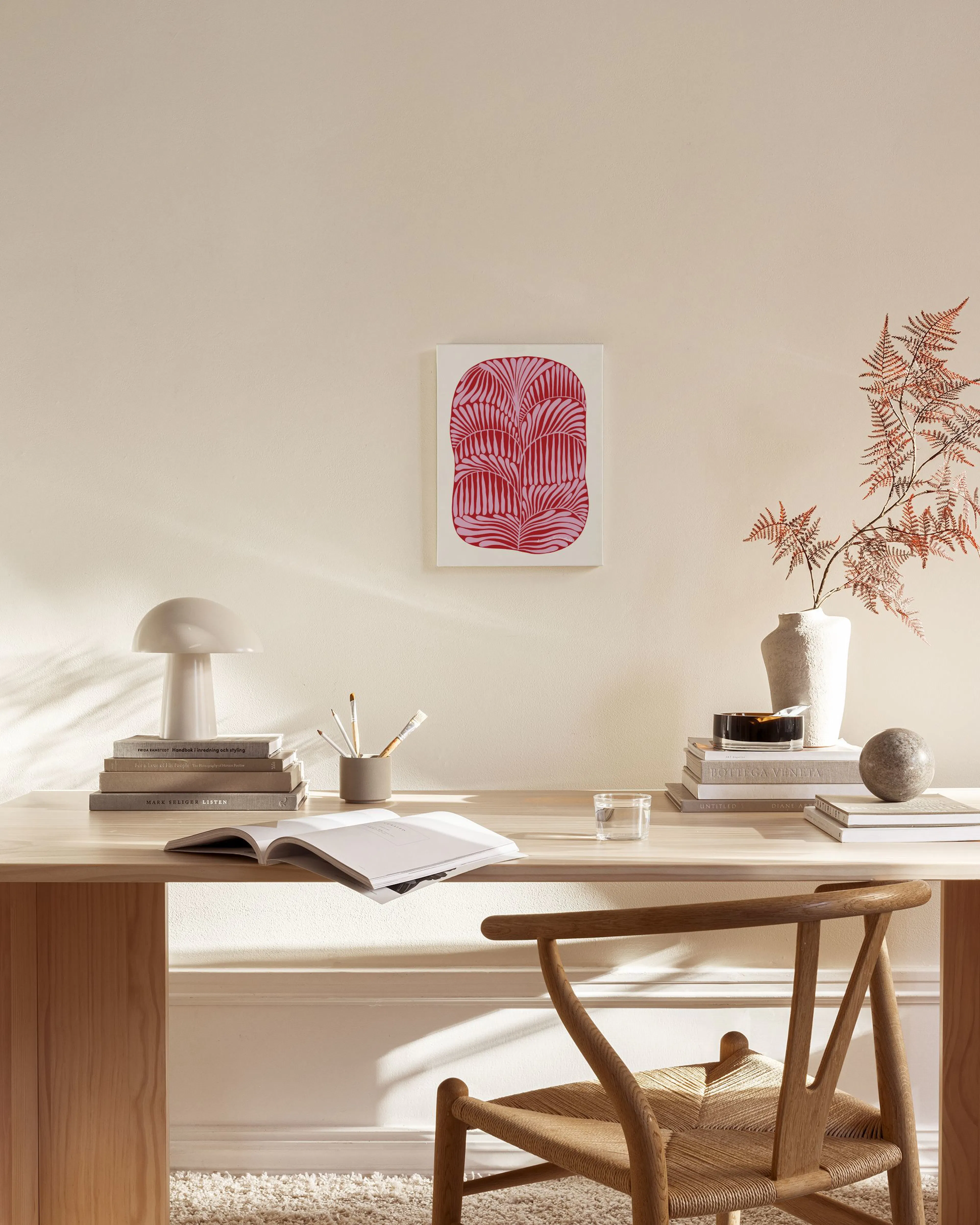 Canvas met roze en rode organische vormen, hangend boven een houten dressoir in een moderne woonkamer.