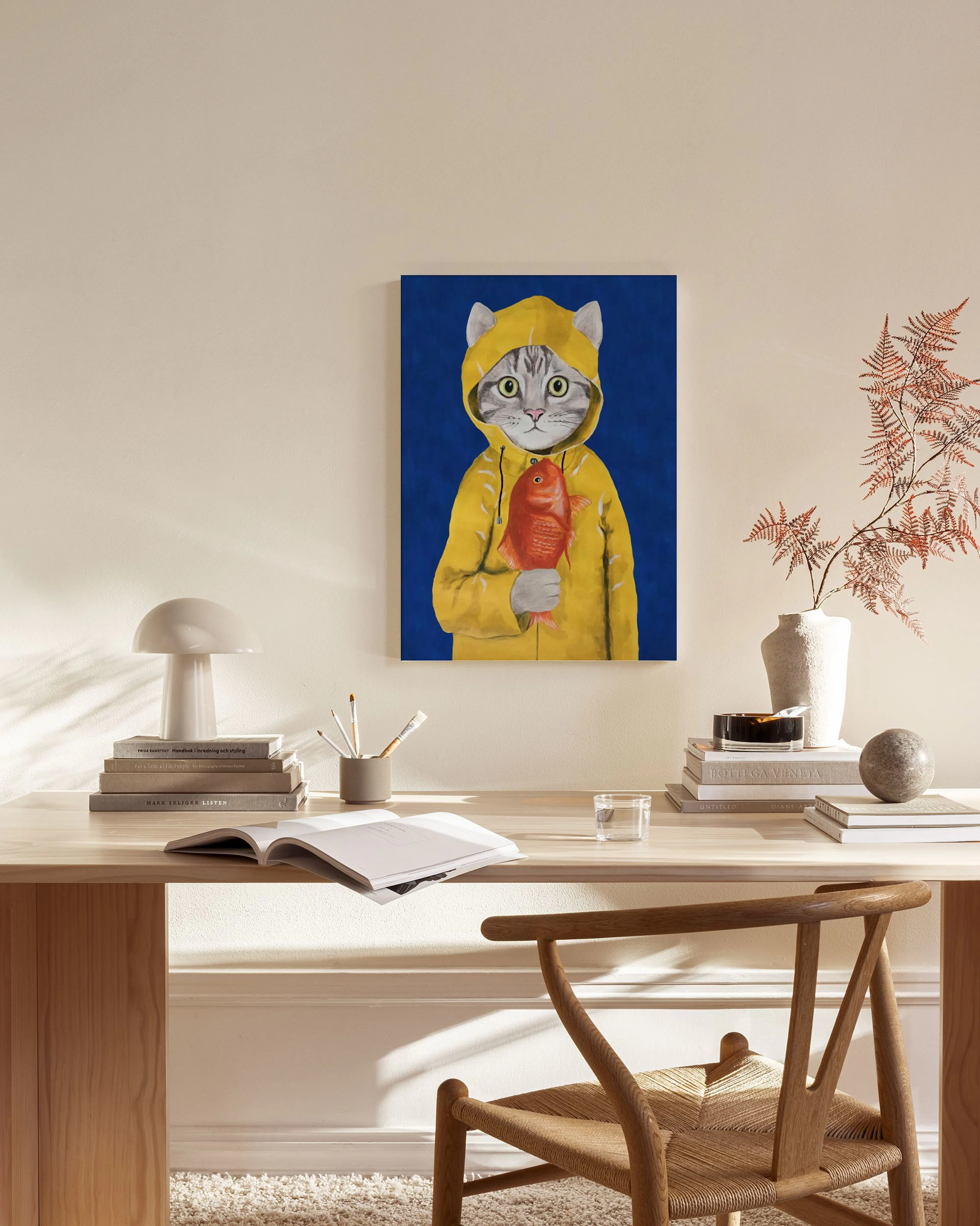Leinwandbild einer Katze in gelbem Regenmantel mit rotem Fisch, hängt im modern eingerichteten Wohnzimmer.