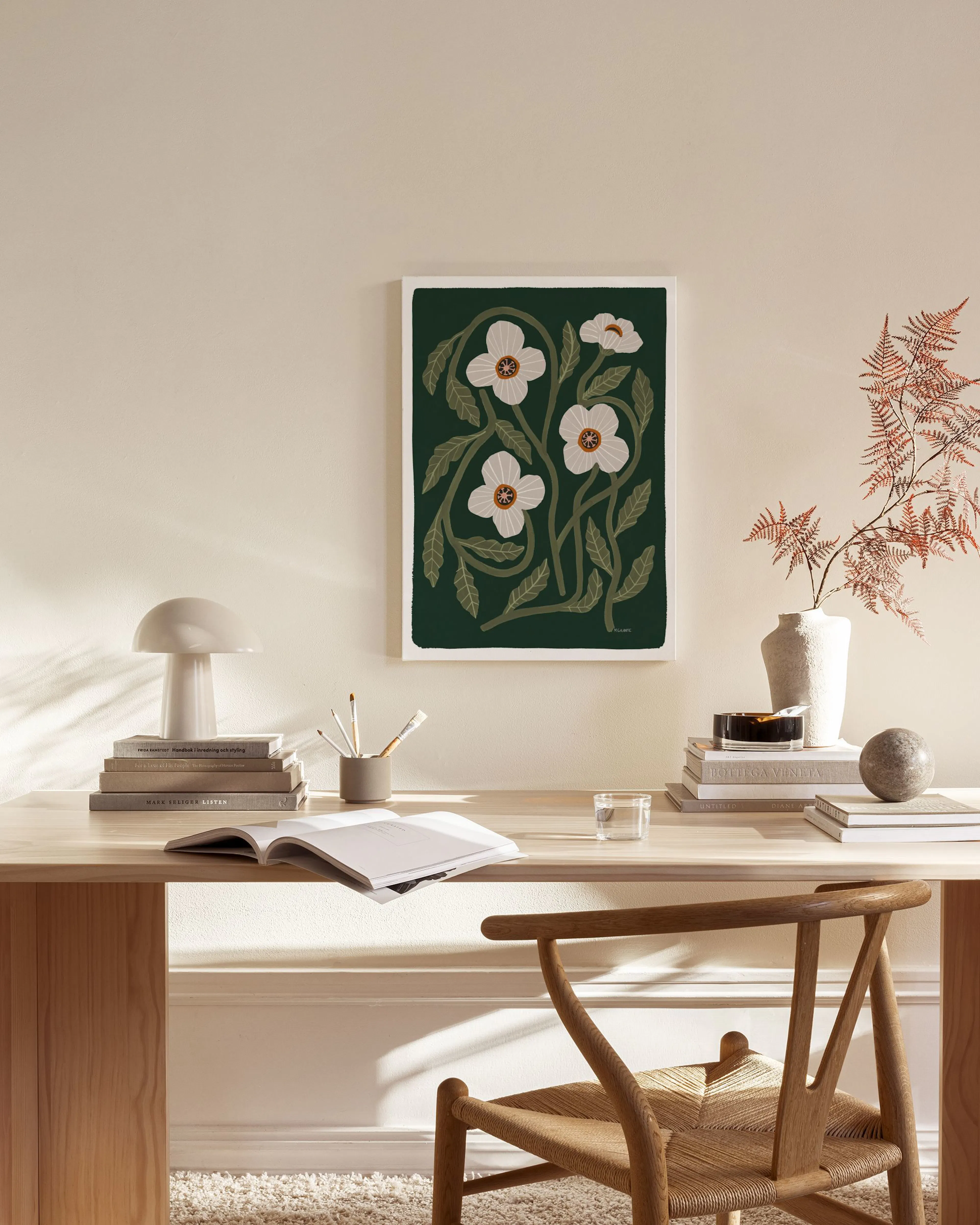A canvas print of white flowers and green leaves on a dark green background, hanging in a modern living room.