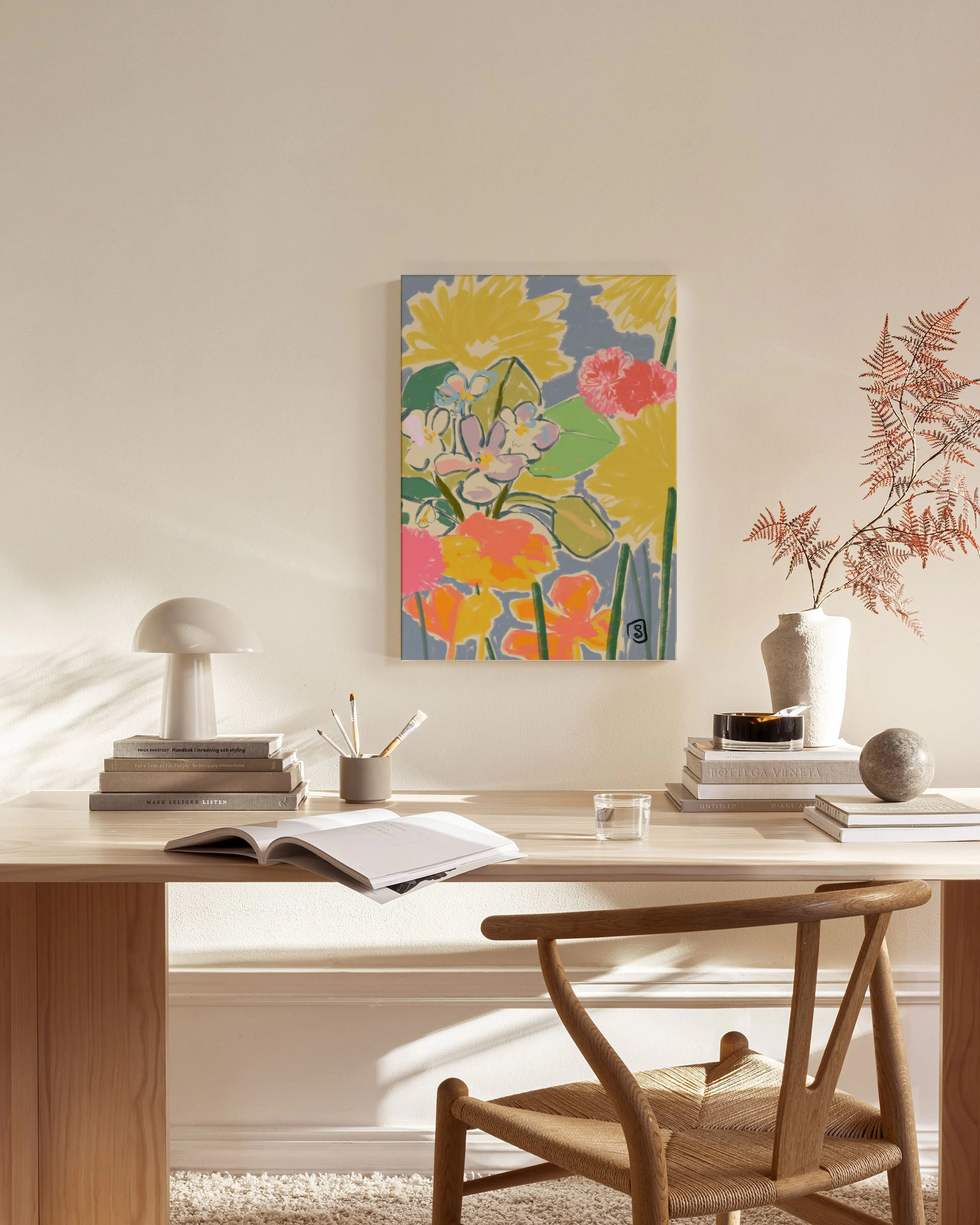 A vibrant floral canvas print with yellow, pink, and orange flowers on a blue background, displayed in a modern living room.
