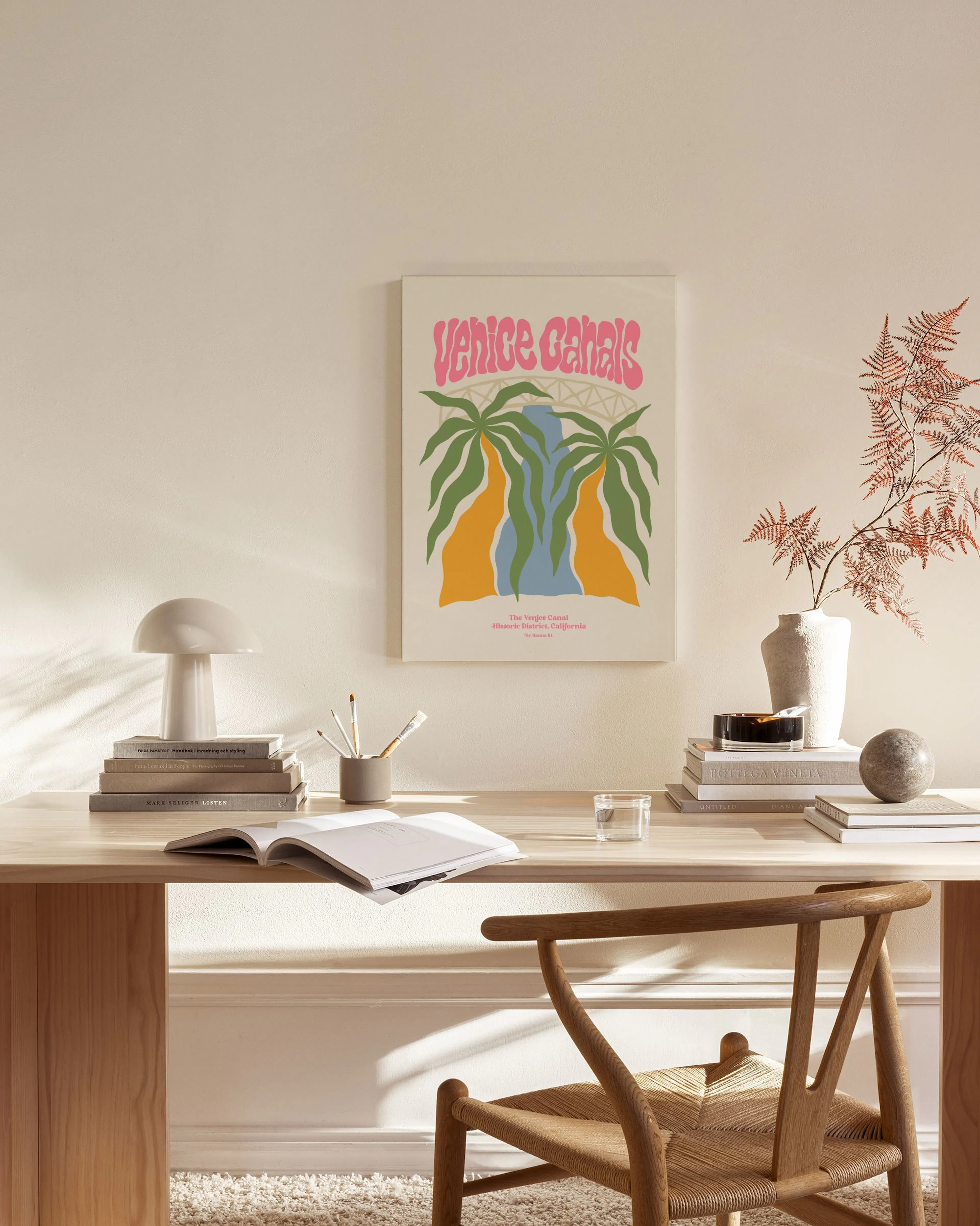 Canvas met roze Venice Canals tekst en palmbomen, hangend boven een houten dressoir in een lichte woonkamer.