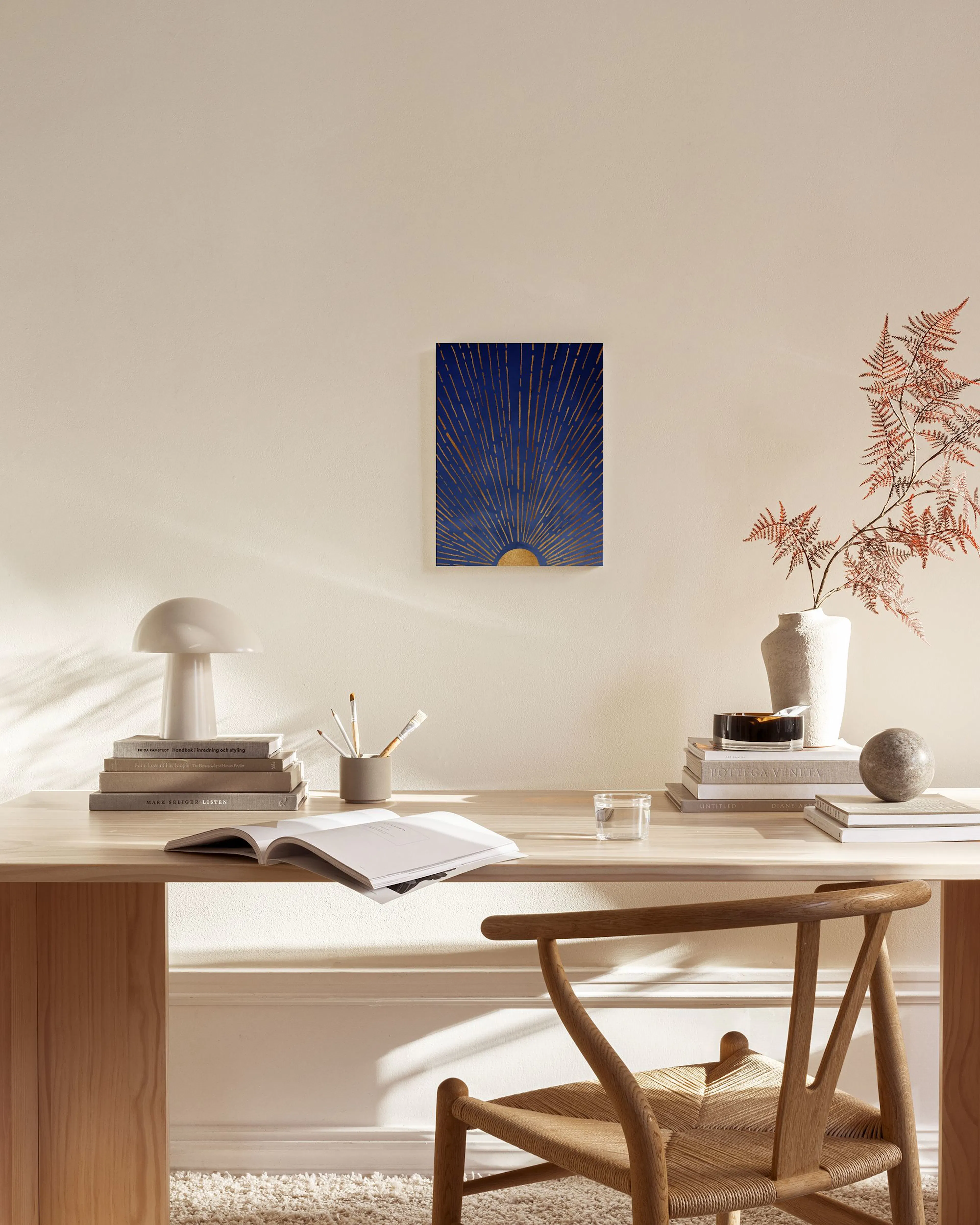 A canvas print of a golden sun rising on a deep blue background, hanging in a light-filled living room above a wooden console.
