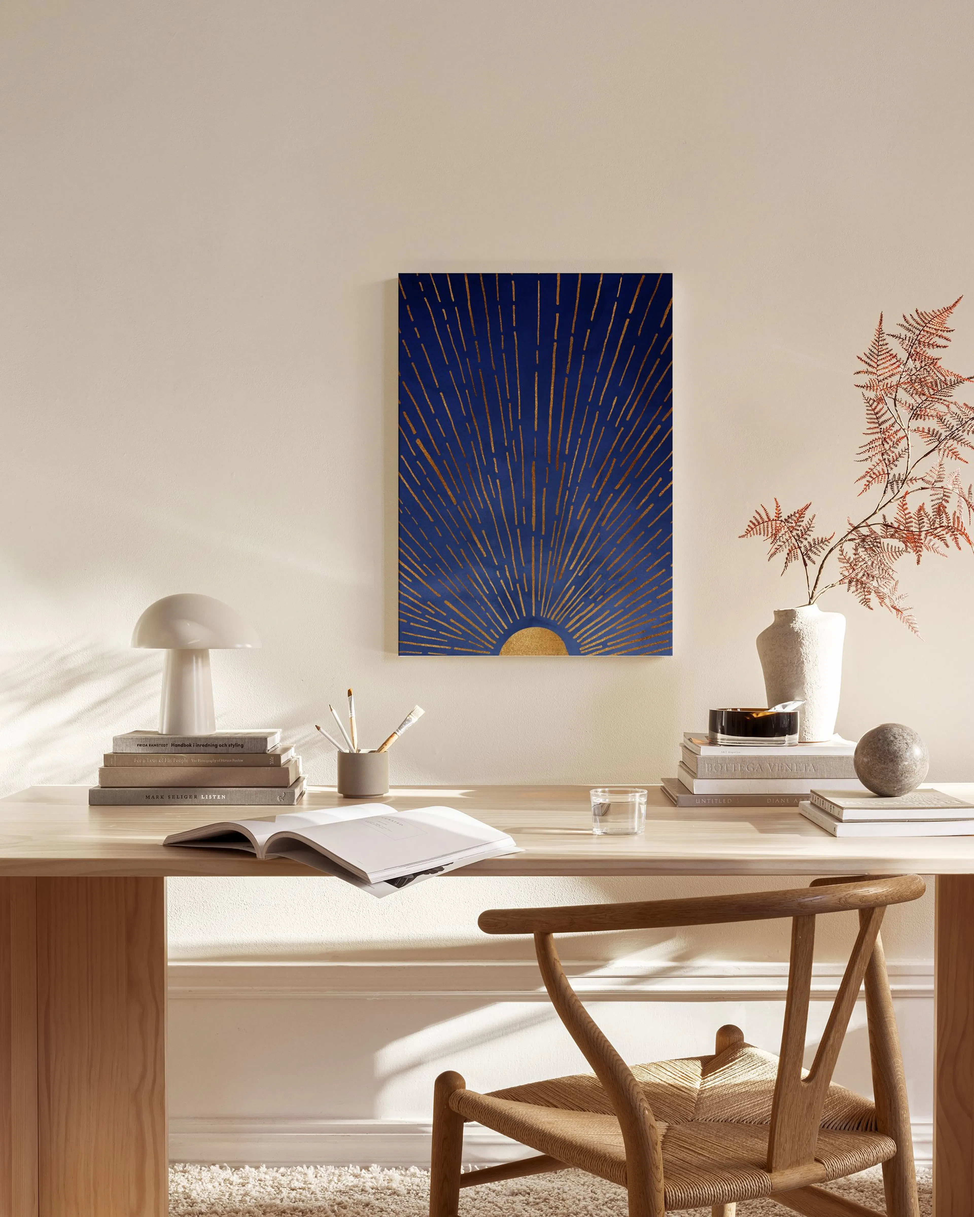 Lienzo con un sol dorado sobre fondo azul oscuro, colgado sobre un mueble bajo de madera en una sala de estar moderna.