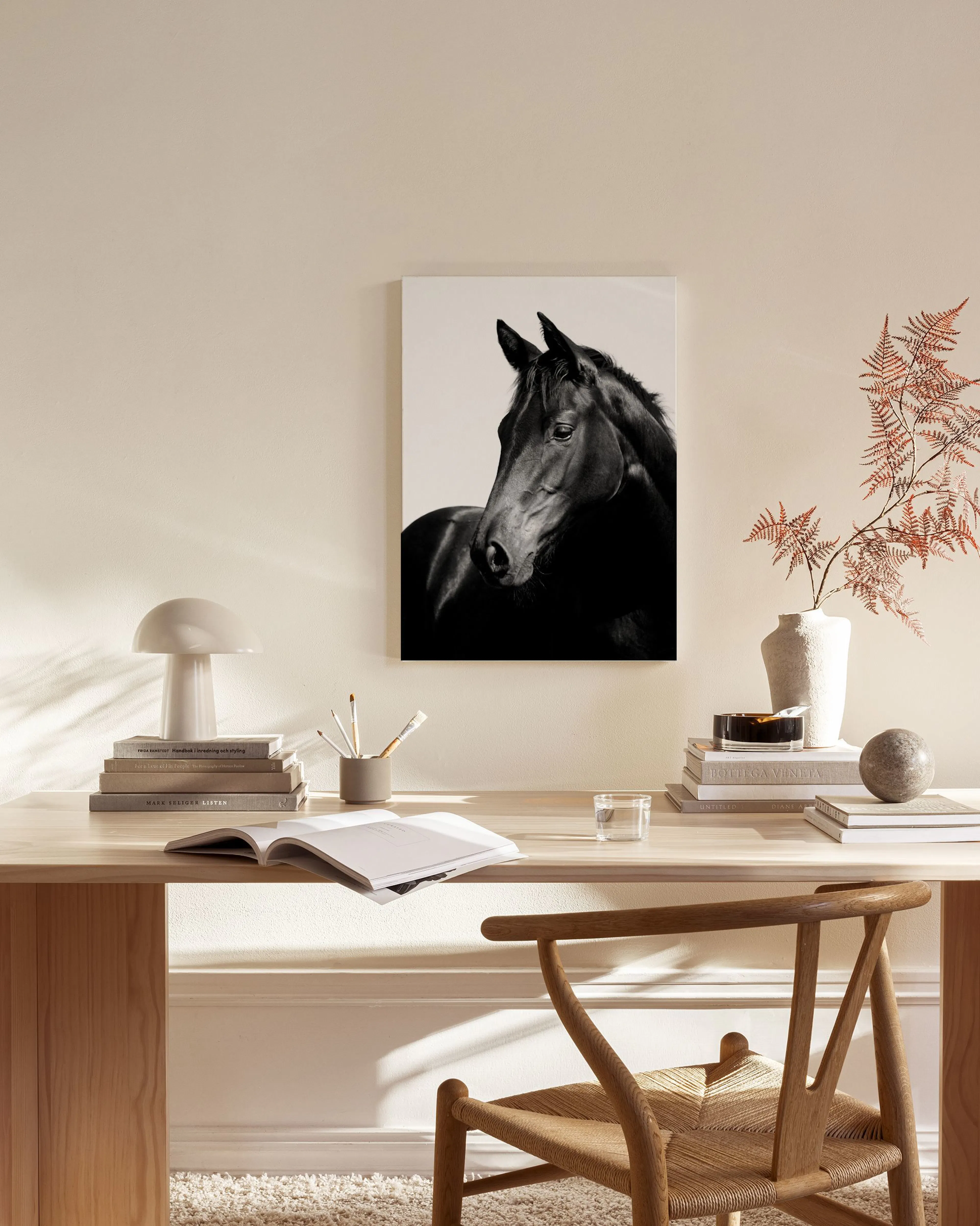 Black and white horse looking right, hanging above a wooden console table in a minimalist living room.