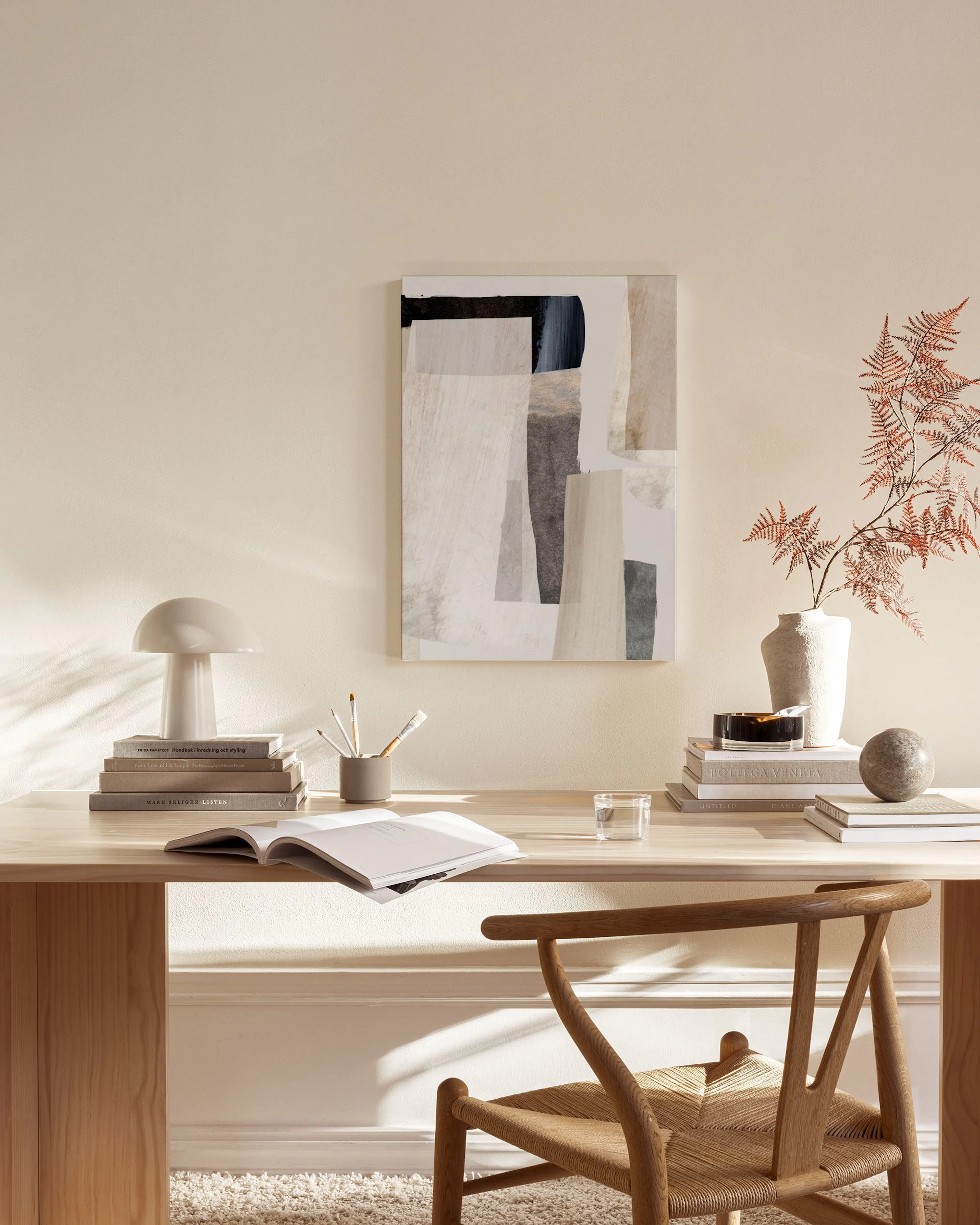 Leinwandbild mit abstrakten Formen in Beige, Grau und Schwarz, über einem Sideboard in einem modernen Wohnzimmer.