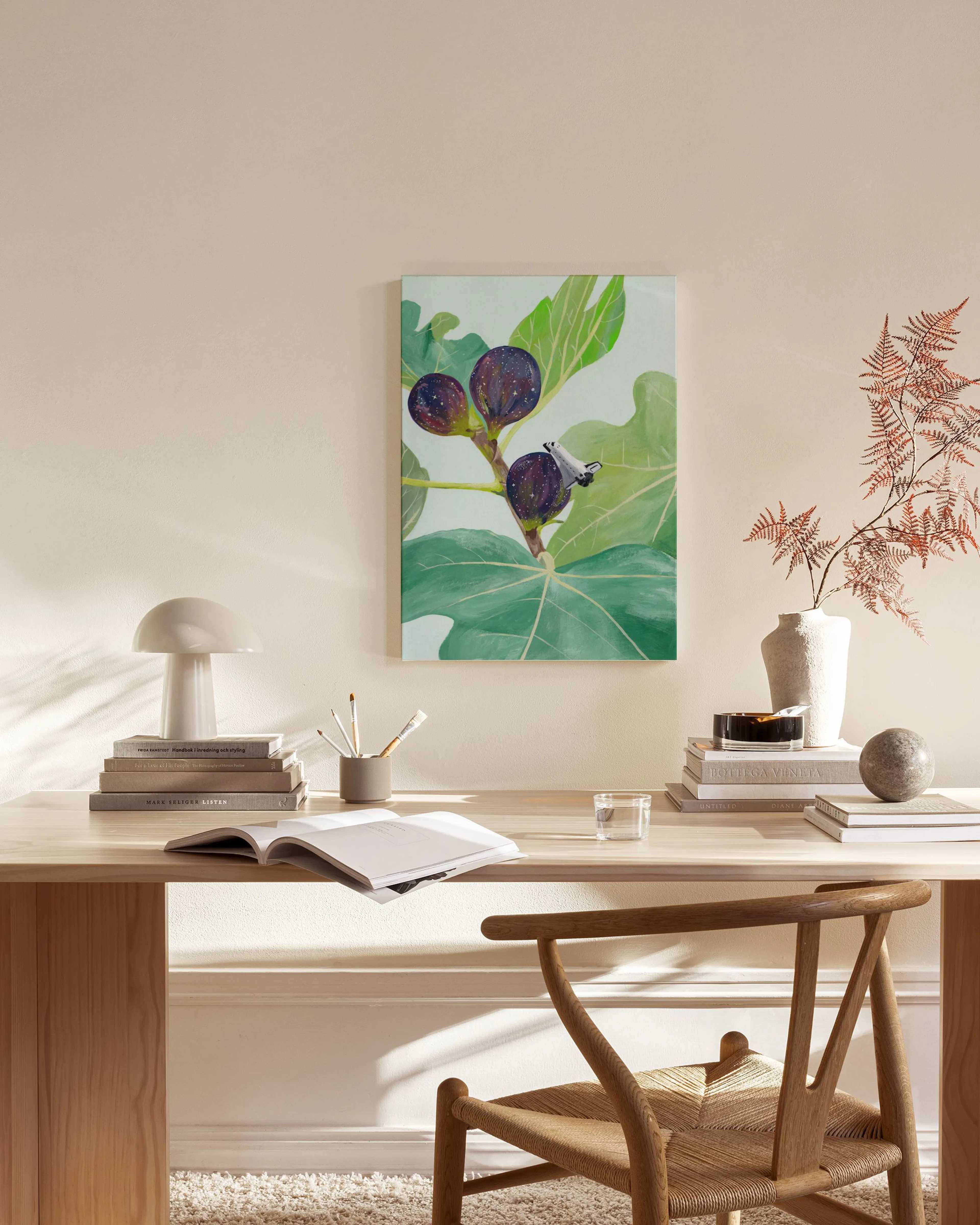 Lienzo de higos morados y hojas verdes, colgado en una sala moderna con un sillón de madera y una mesa de café.