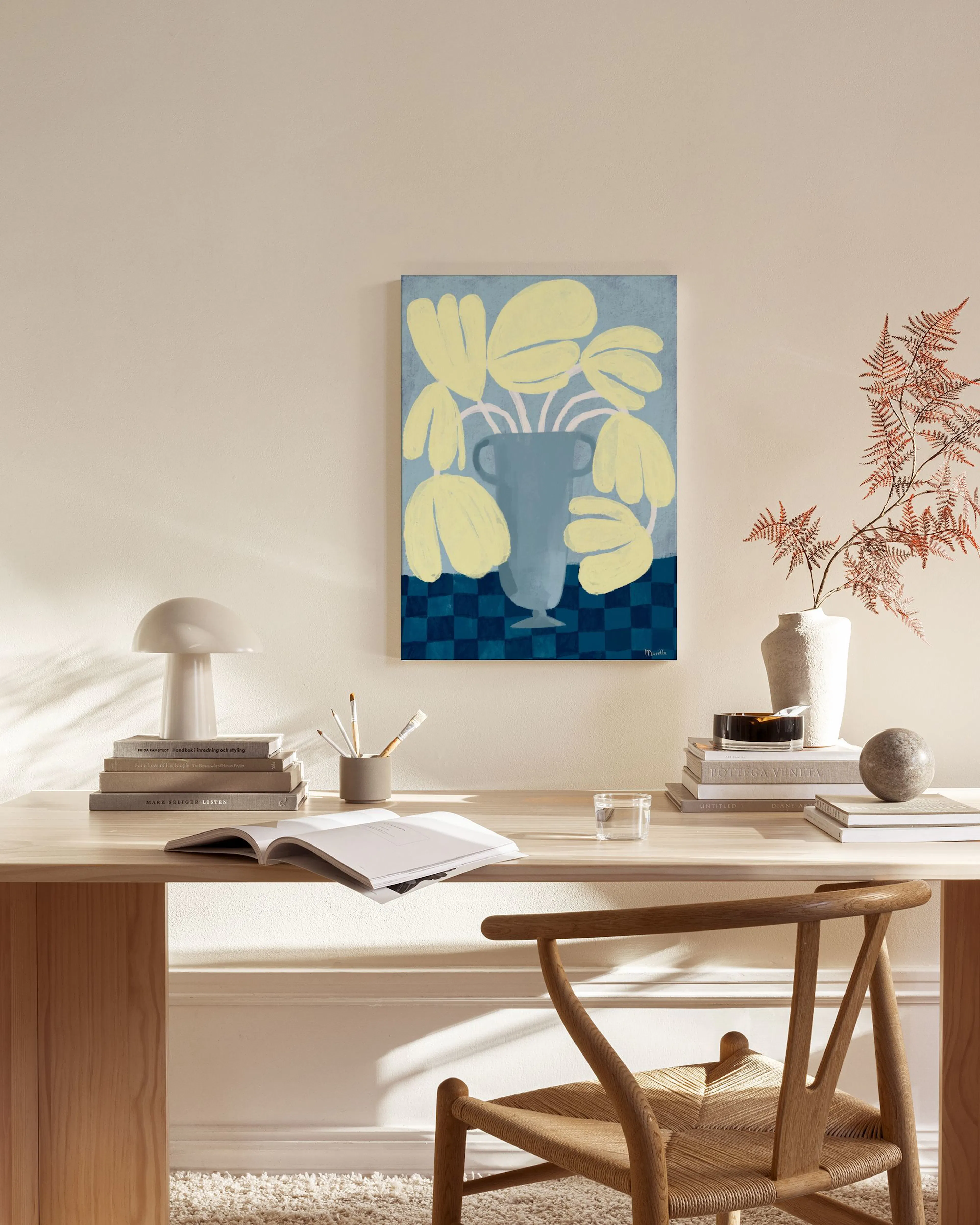 A canvas print of yellow flowers in a gray vase on a blue checkered table, hanging in a bright living room.