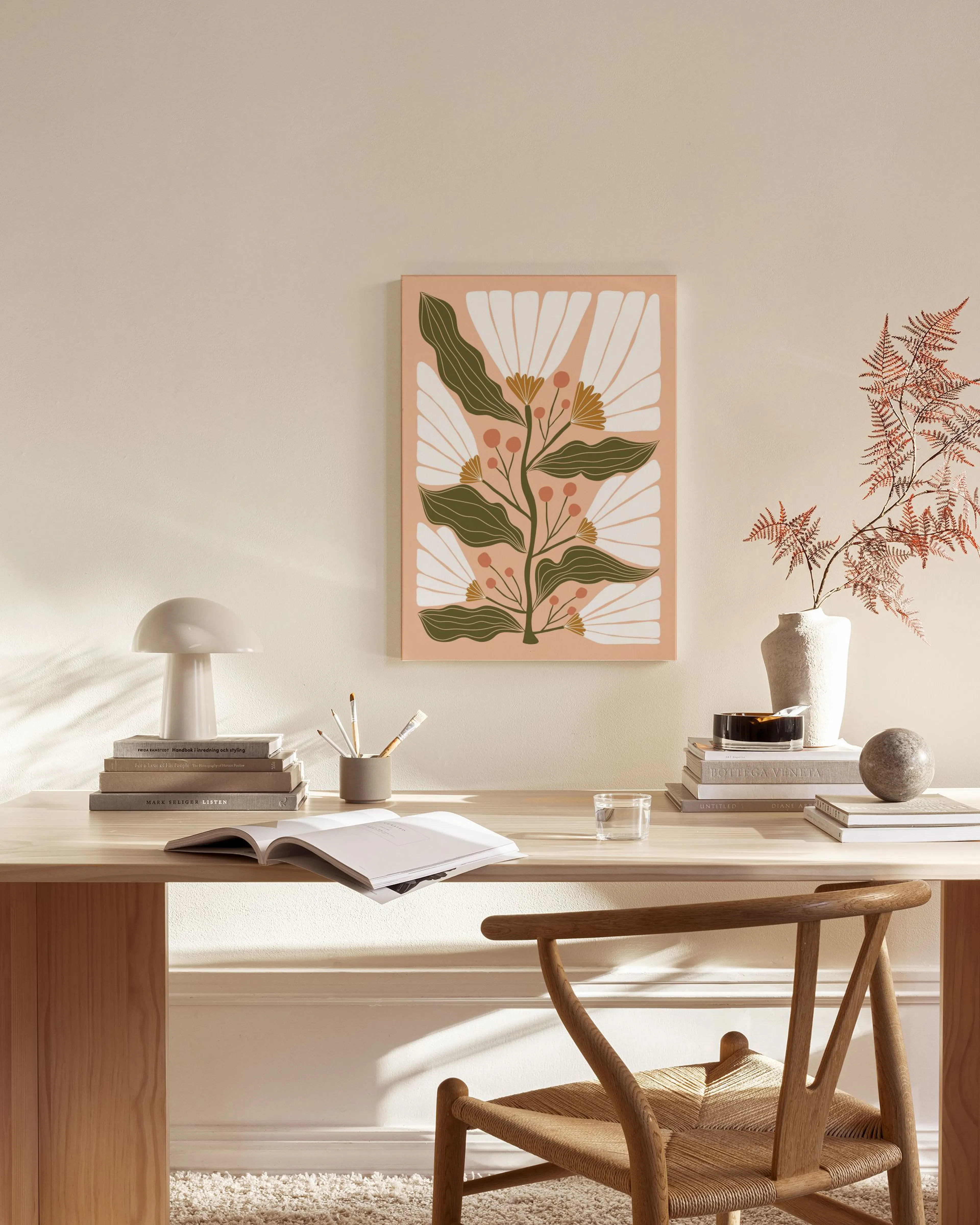 Botanical canvas print with white flowers, dark green leaves, and orange berries on a light pink background, hanging in a modern