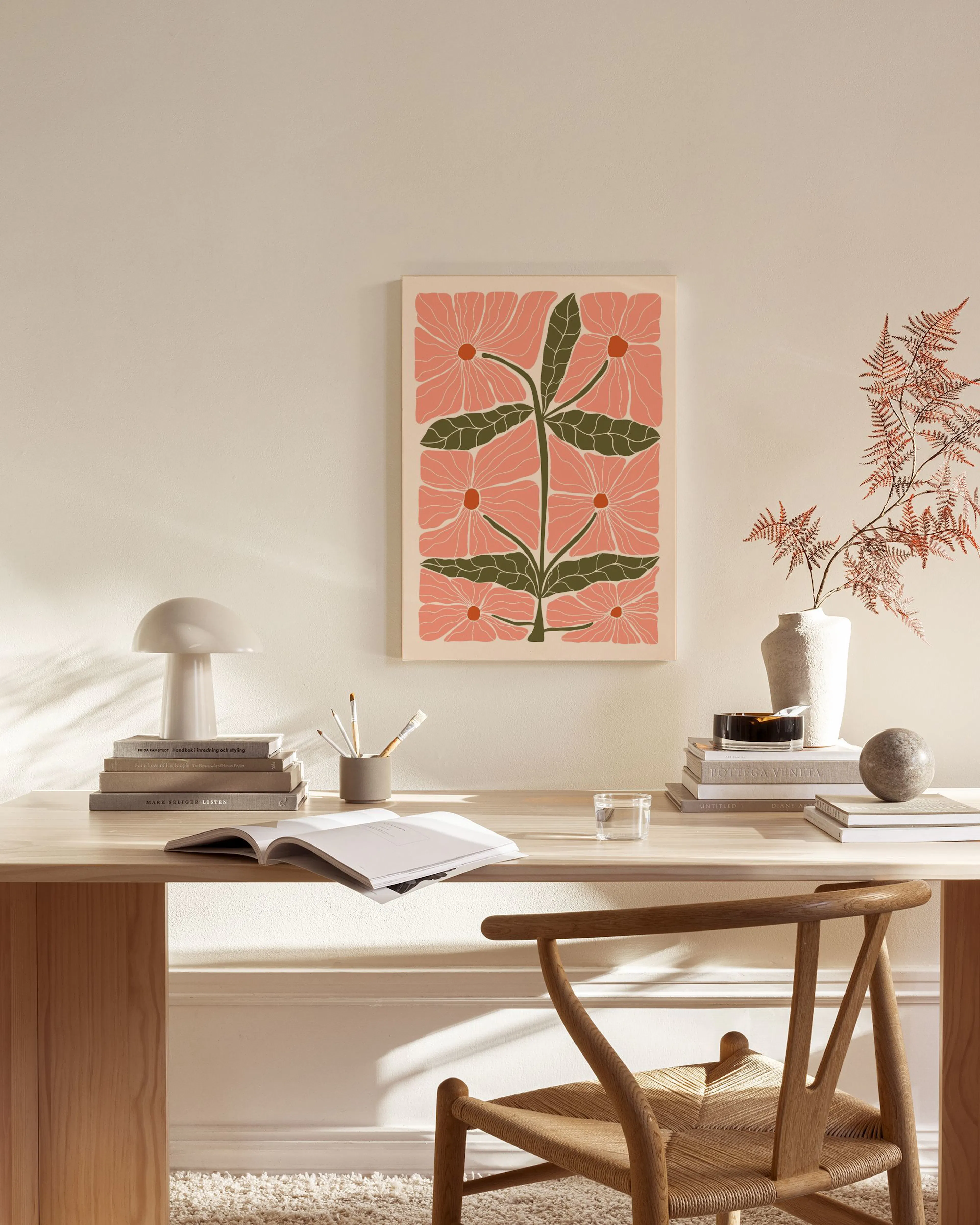 Botanical print with pink flowers and green leaves, hanging above a wooden console table in a living room.