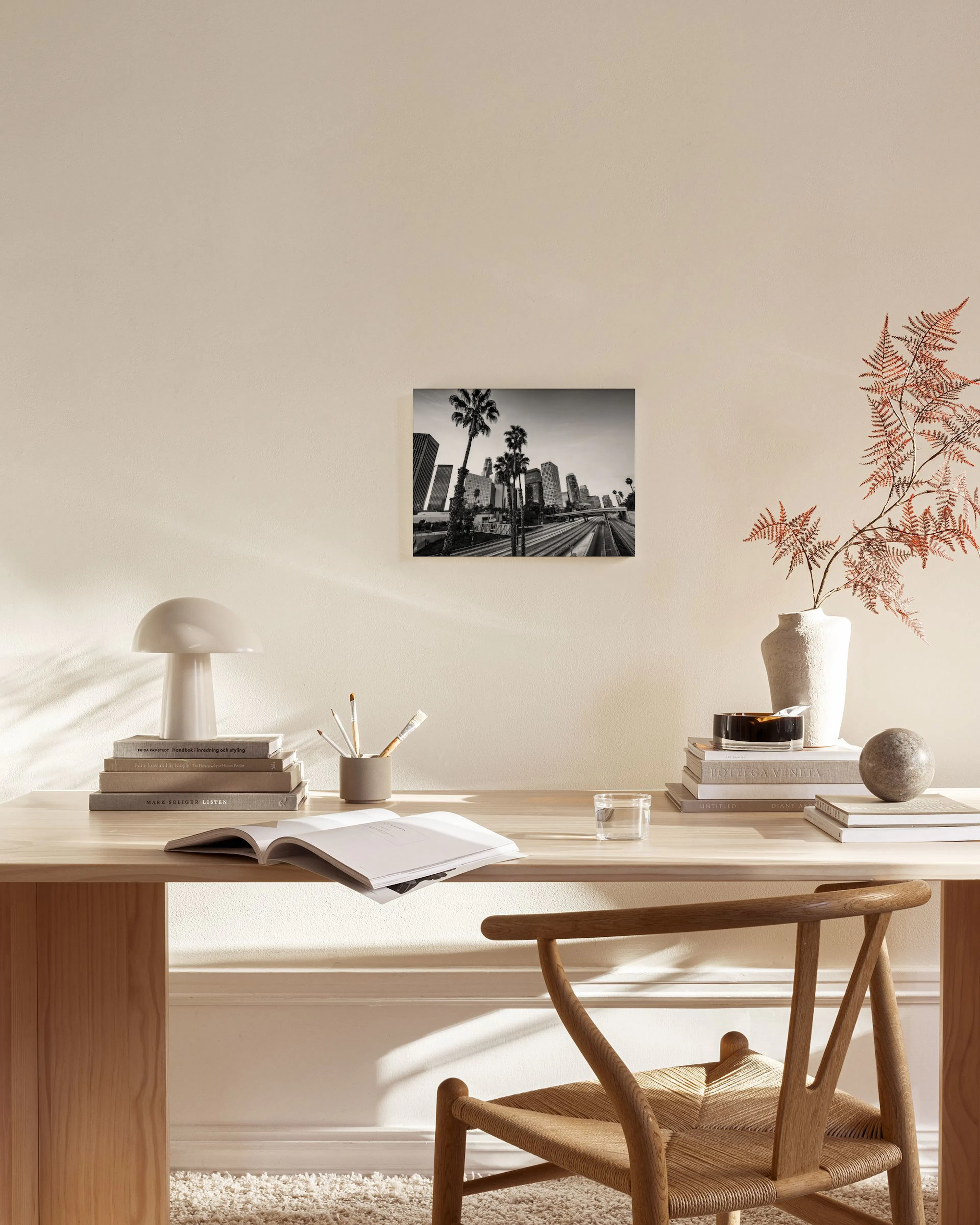 Black and white cityscape canvas print with palm trees and modern buildings, hanging in a bright, minimalist living room.