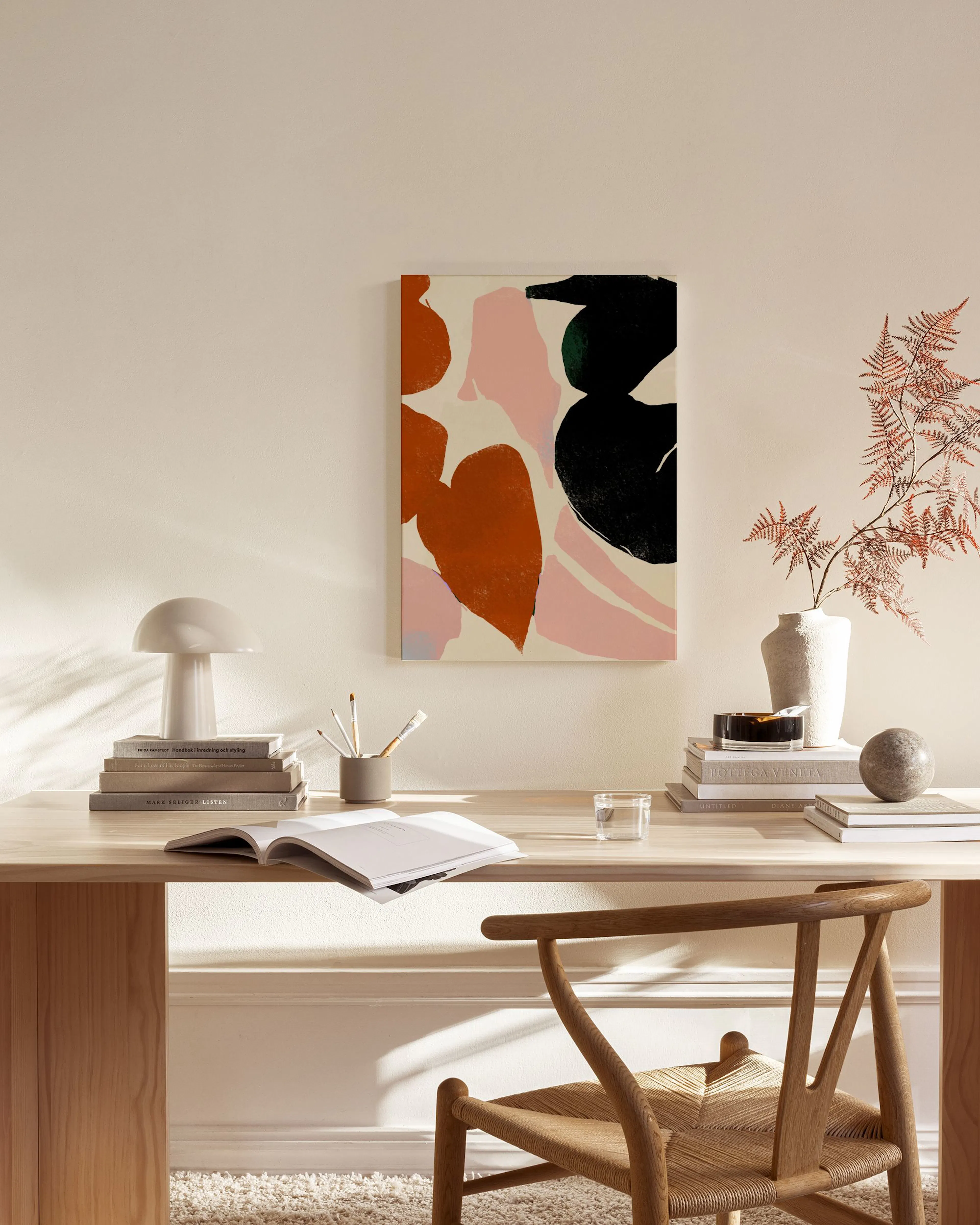 Leinwandbild mit abstrakten Formen in Terrakotta, Rosa und Schwarz, hängt über einem Holzschrank im Wohnzimmer.