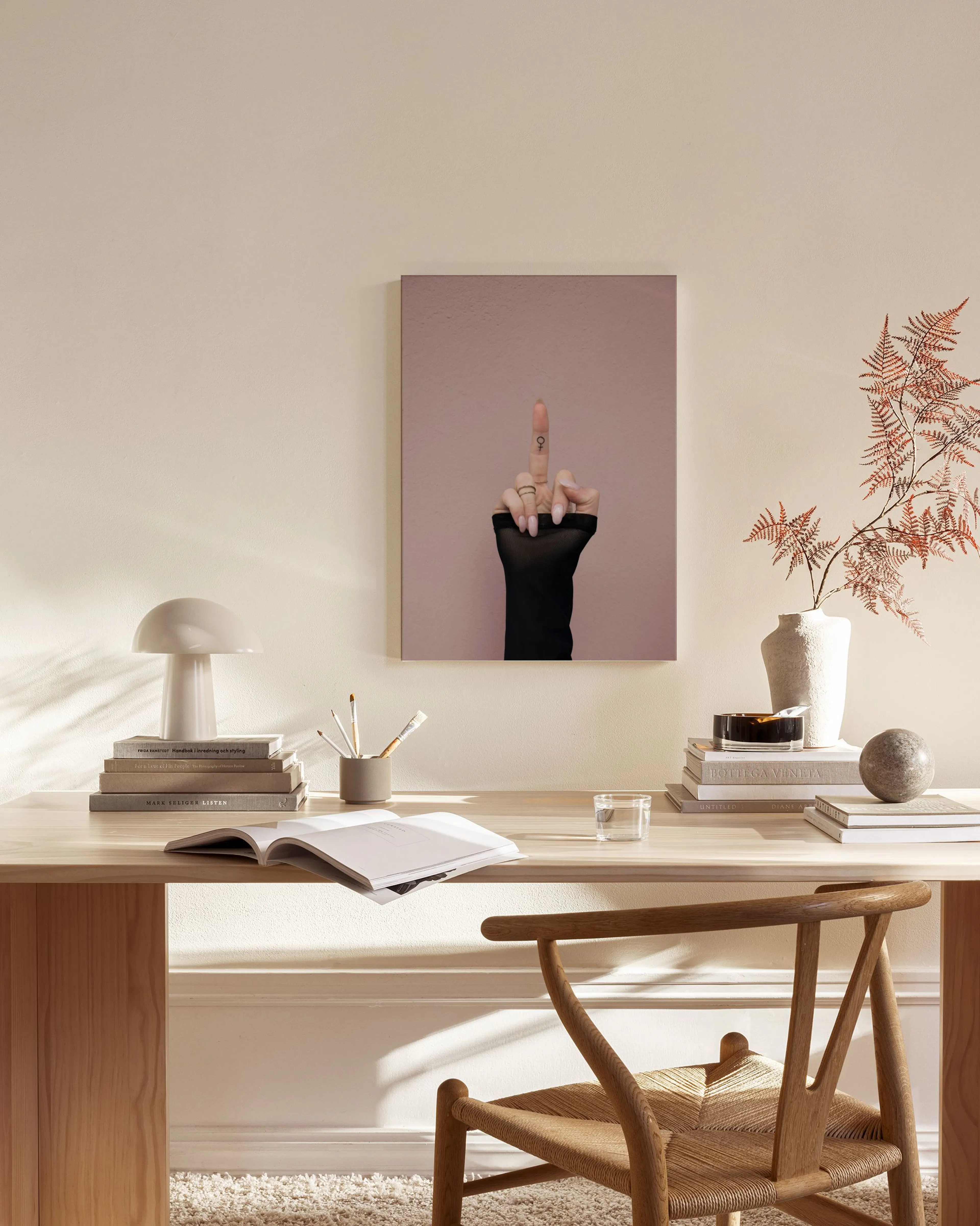 A canvas print of a hand with a middle finger raised, wearing a black mesh glove and a ring, against a pink background, displaye