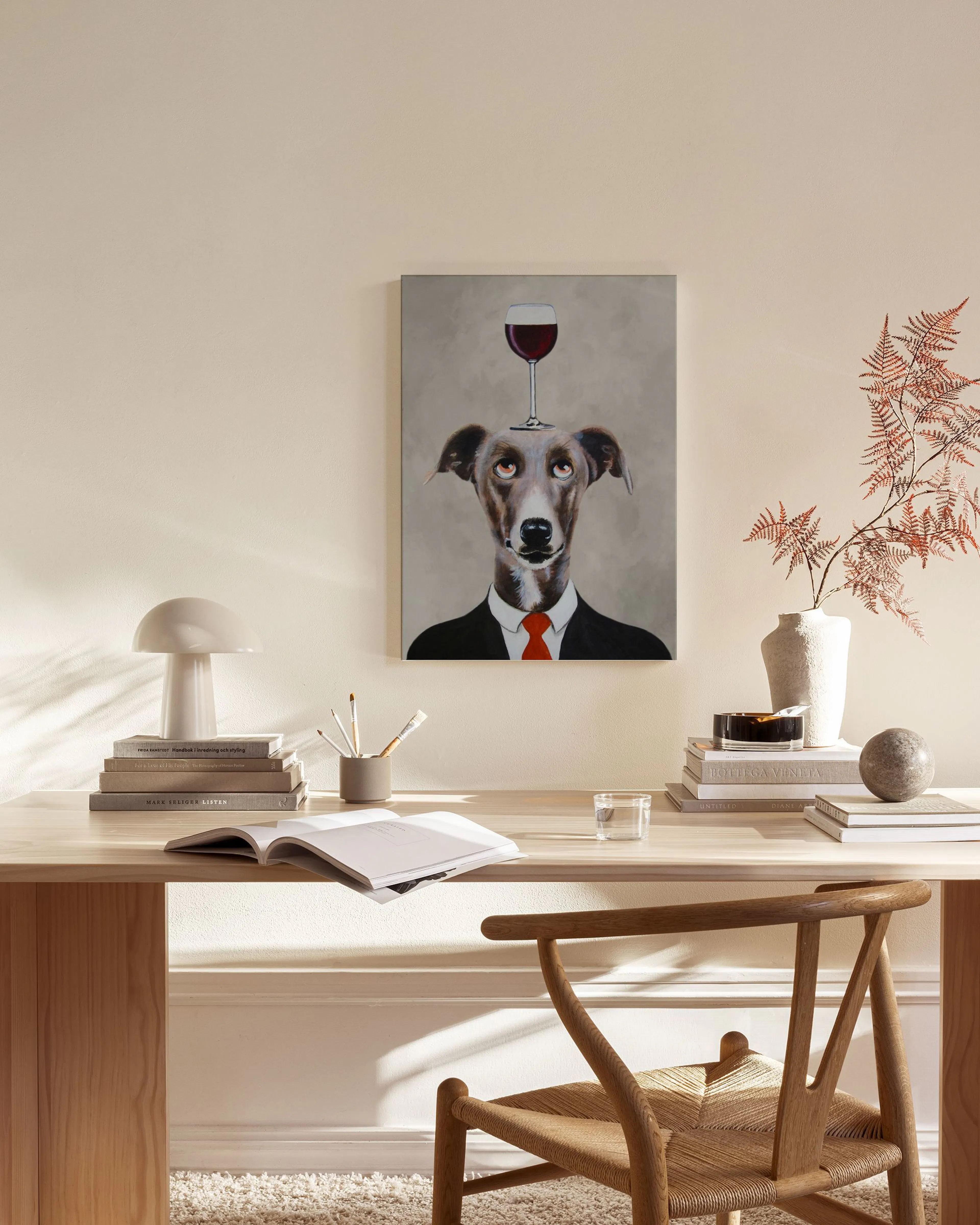 Tela decorativa de um cão galgo com fato e gravata vermelha, com um copo de vinho tinto na cabeça, pendurada numa sala de estar 