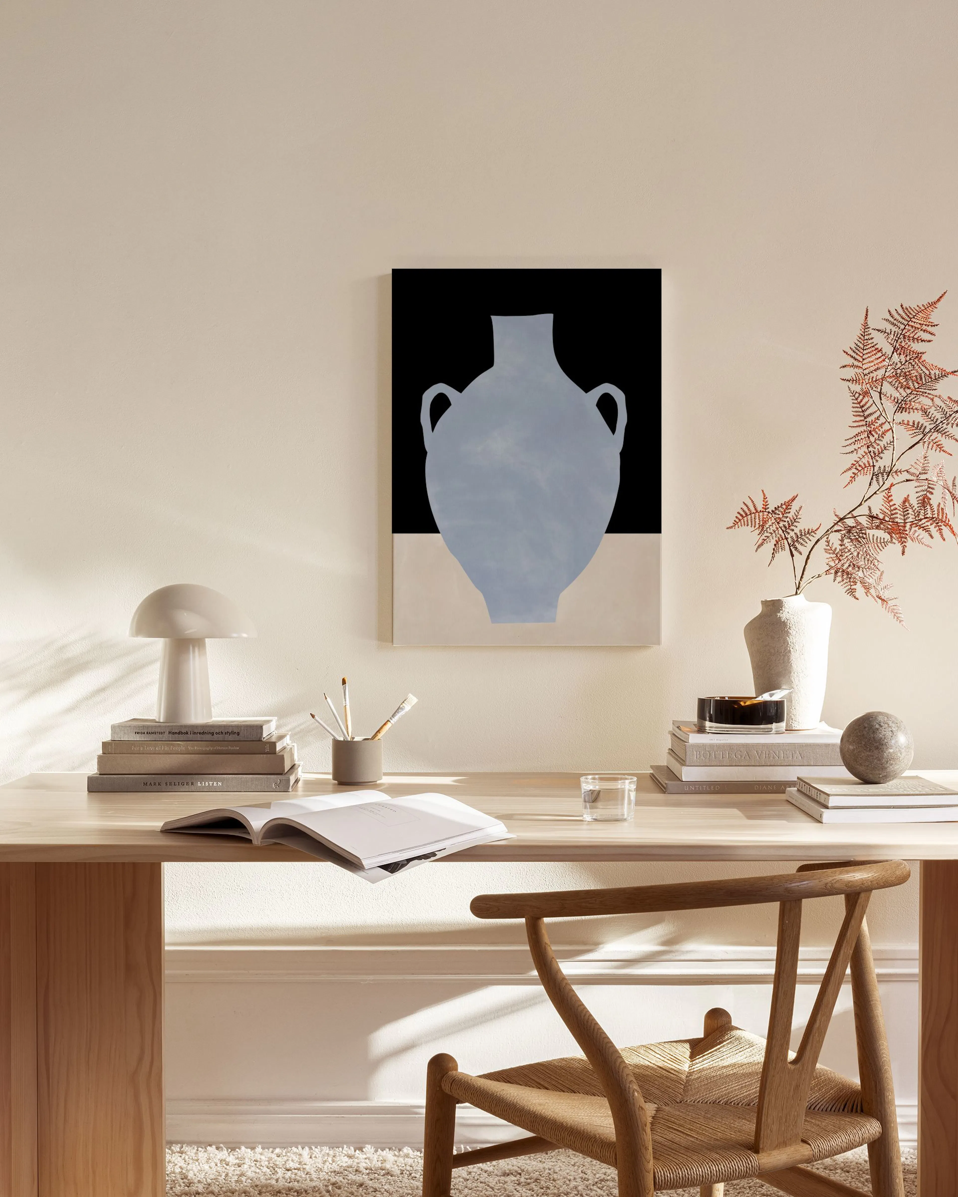 Lienzo con silueta de jarrón azul claro sobre fondo negro y beige, colgado en una sala de estar.