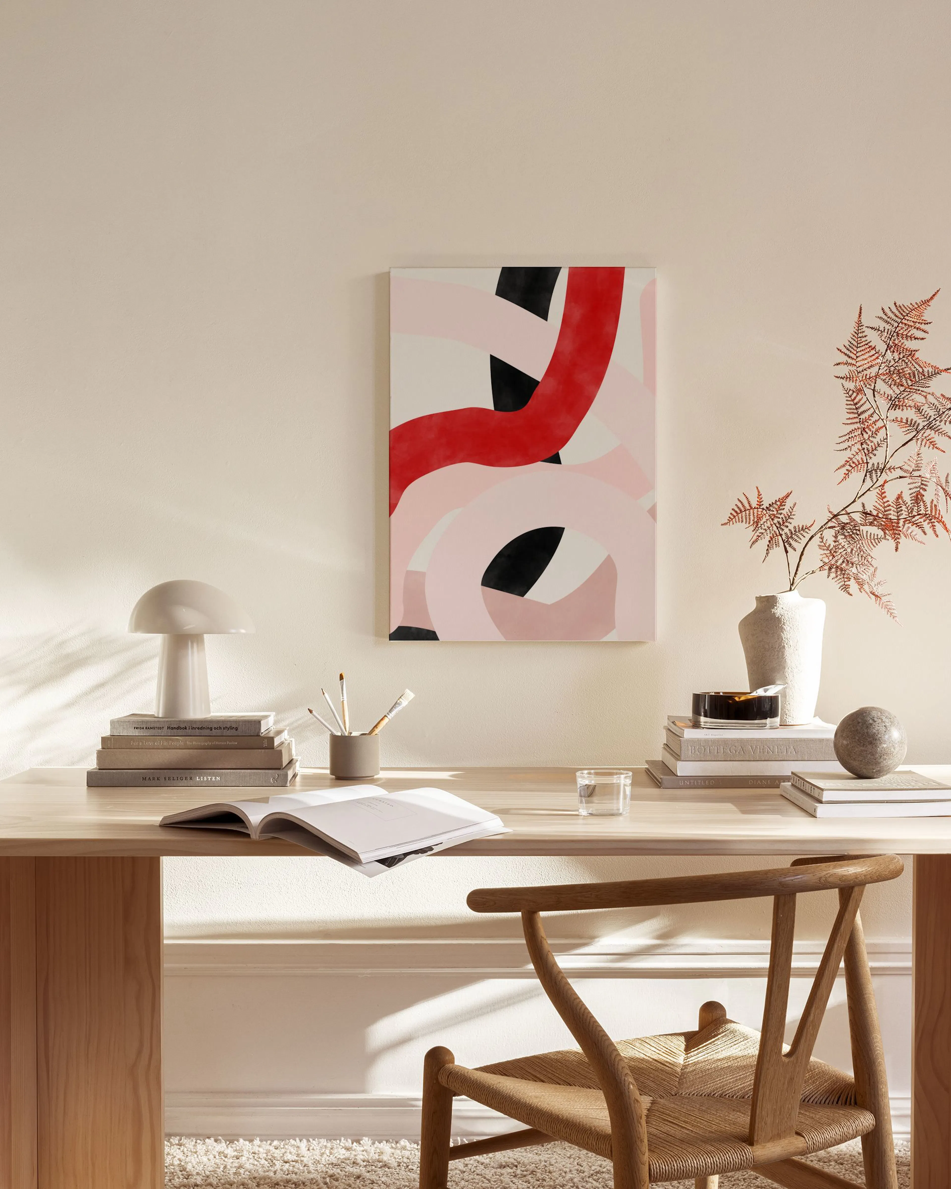 Abstract canvas print with bold red, pale pink, and black curved shapes, displayed in a bright modern living room.